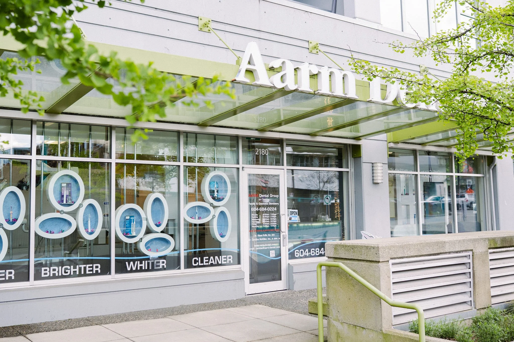 Exterior of a dental clinic named Arim Dental Group, with large glass windows displaying dental products, and signs promoting dental cleaning and whitening services.