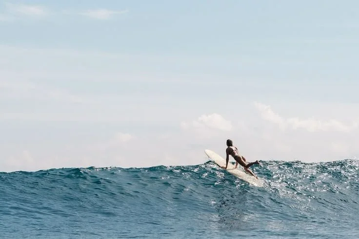 Surfer riding a wave against a blue sky.