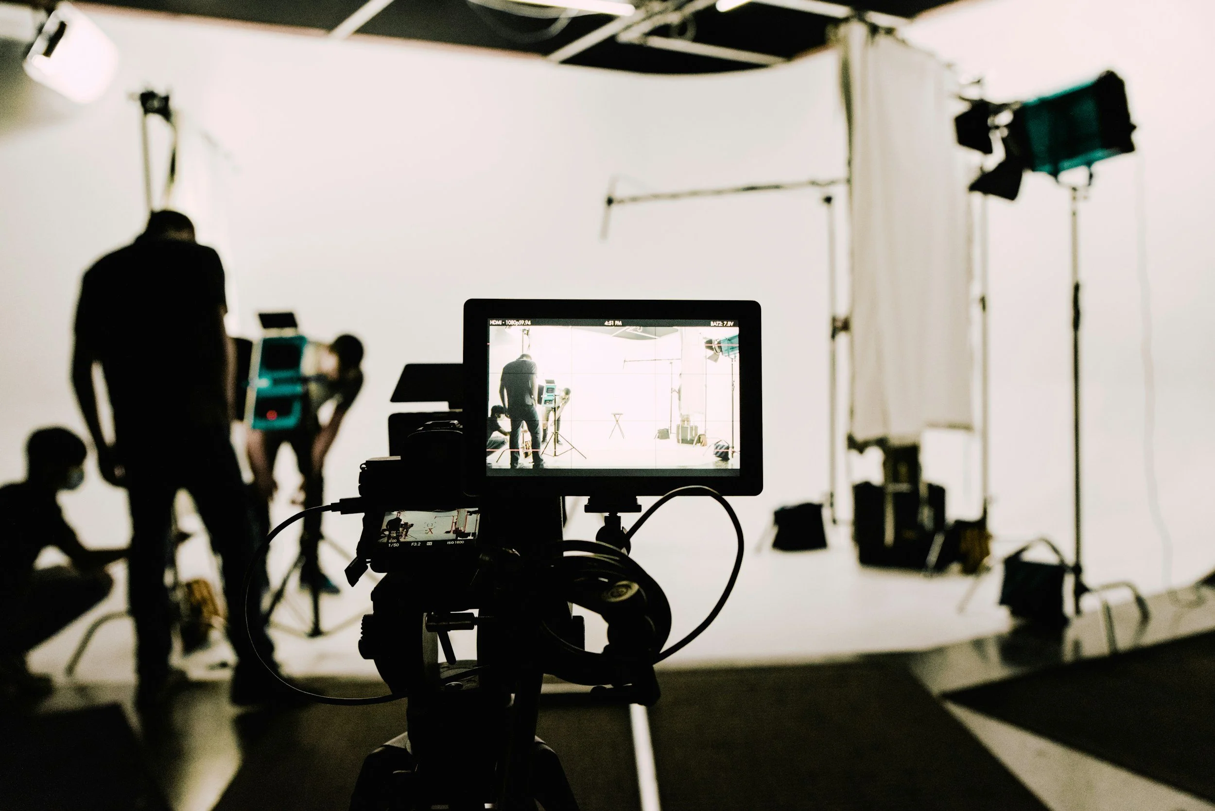 Film crew setting up camera and lighting equipment in a studio