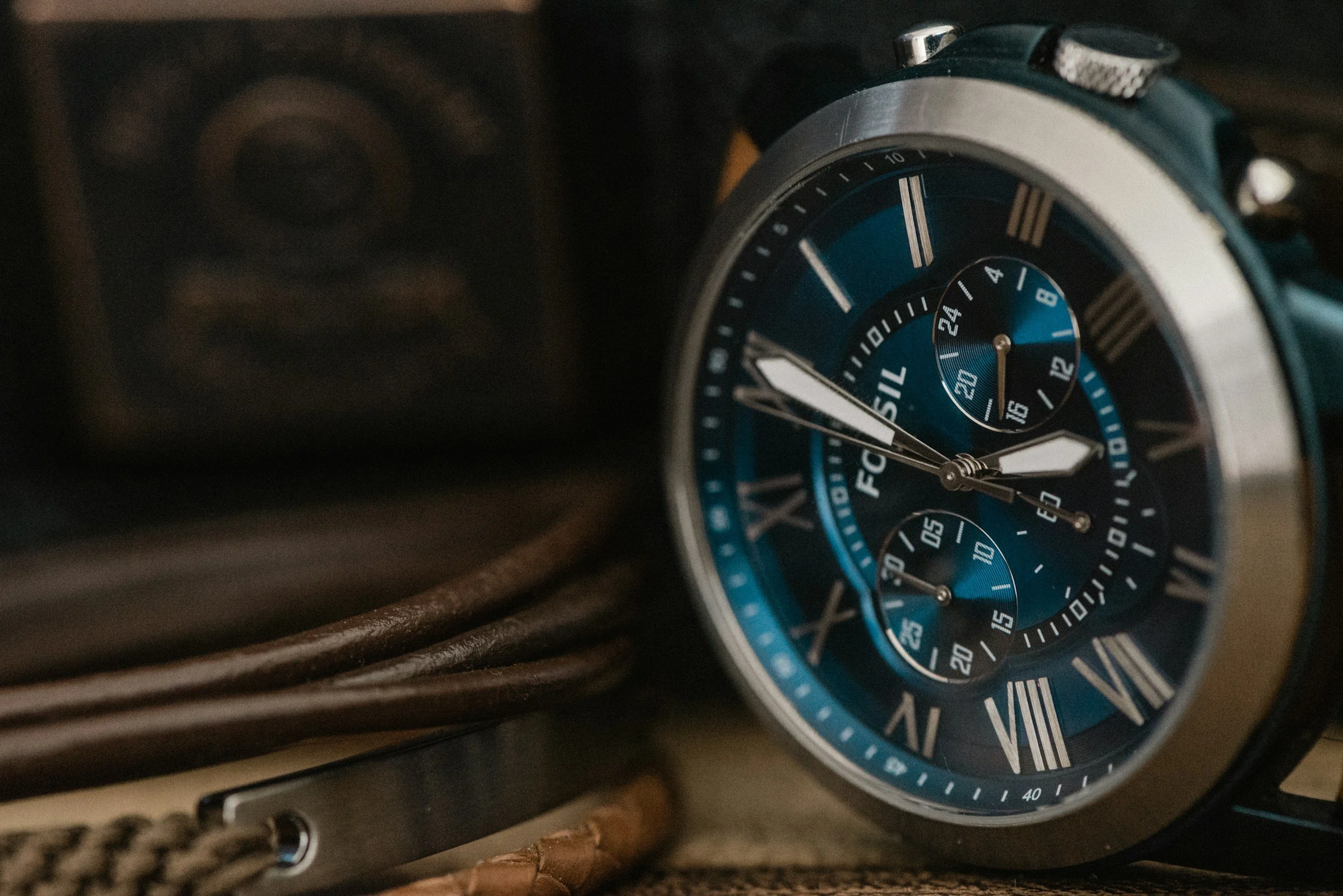 Close-up of a blue and silver wristwatch with Roman numerals and three subdials.