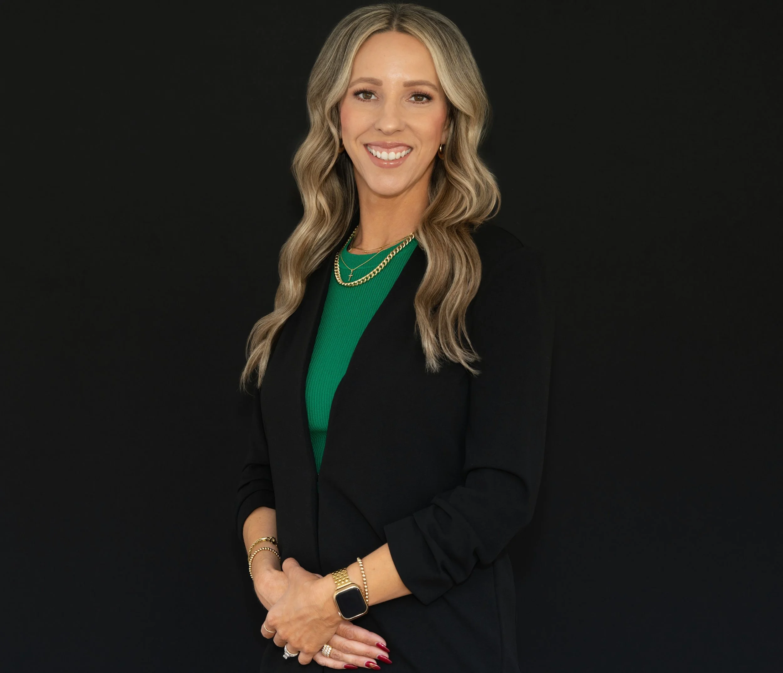 Professional headshot of white female lady blonde long hair arms crossed above waist in front of her smiling black backdrop
