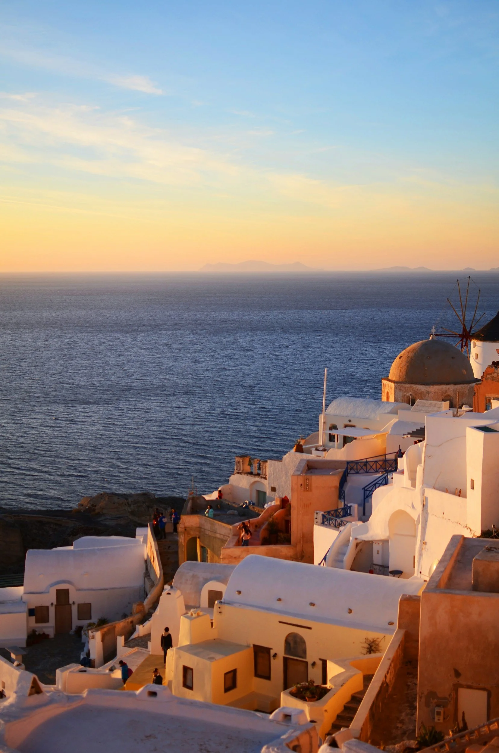 Sunset over white buildings and the sea in Santorini, Greece.