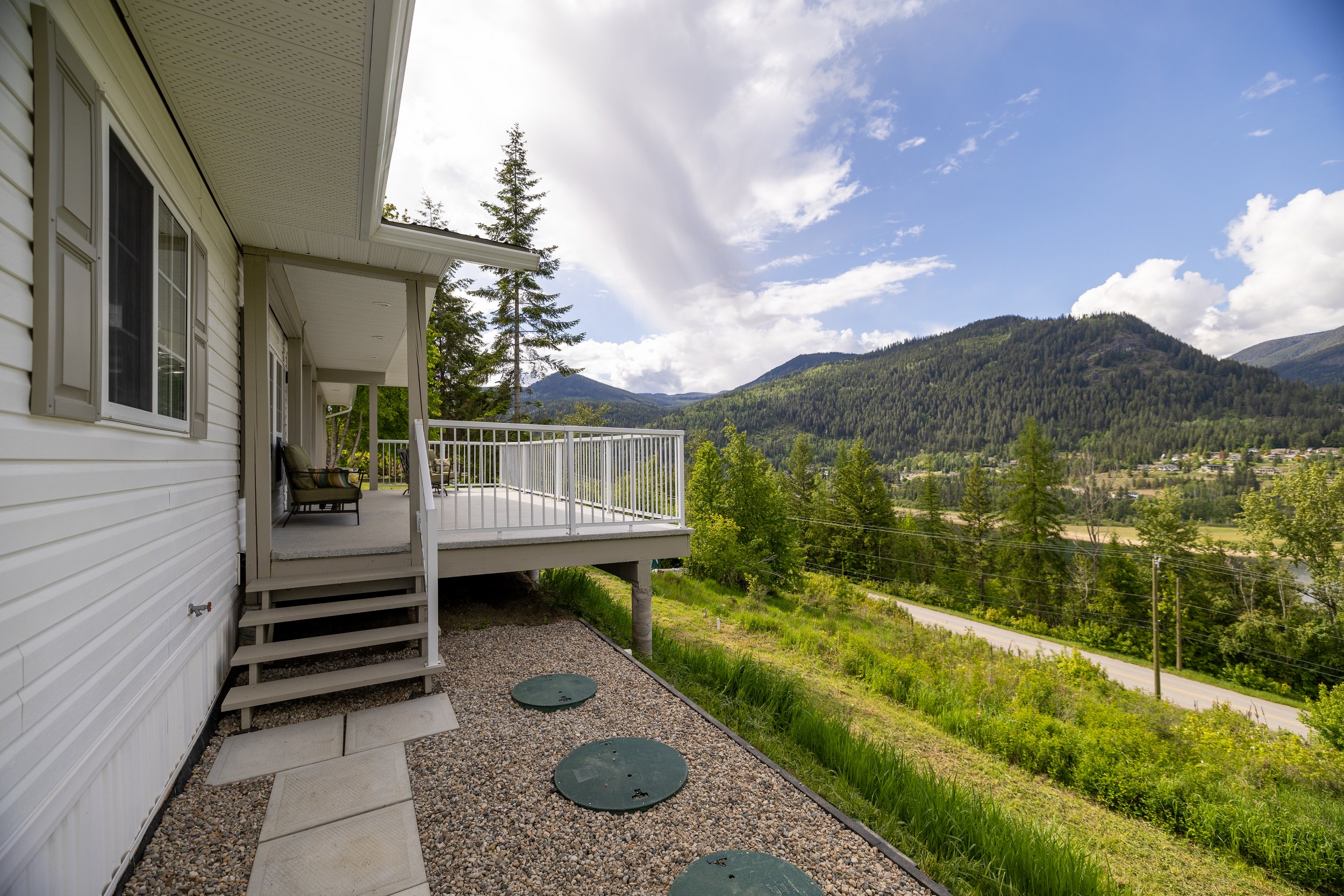 View of a house's back porch with a mountain landscape and blue sky in the background.