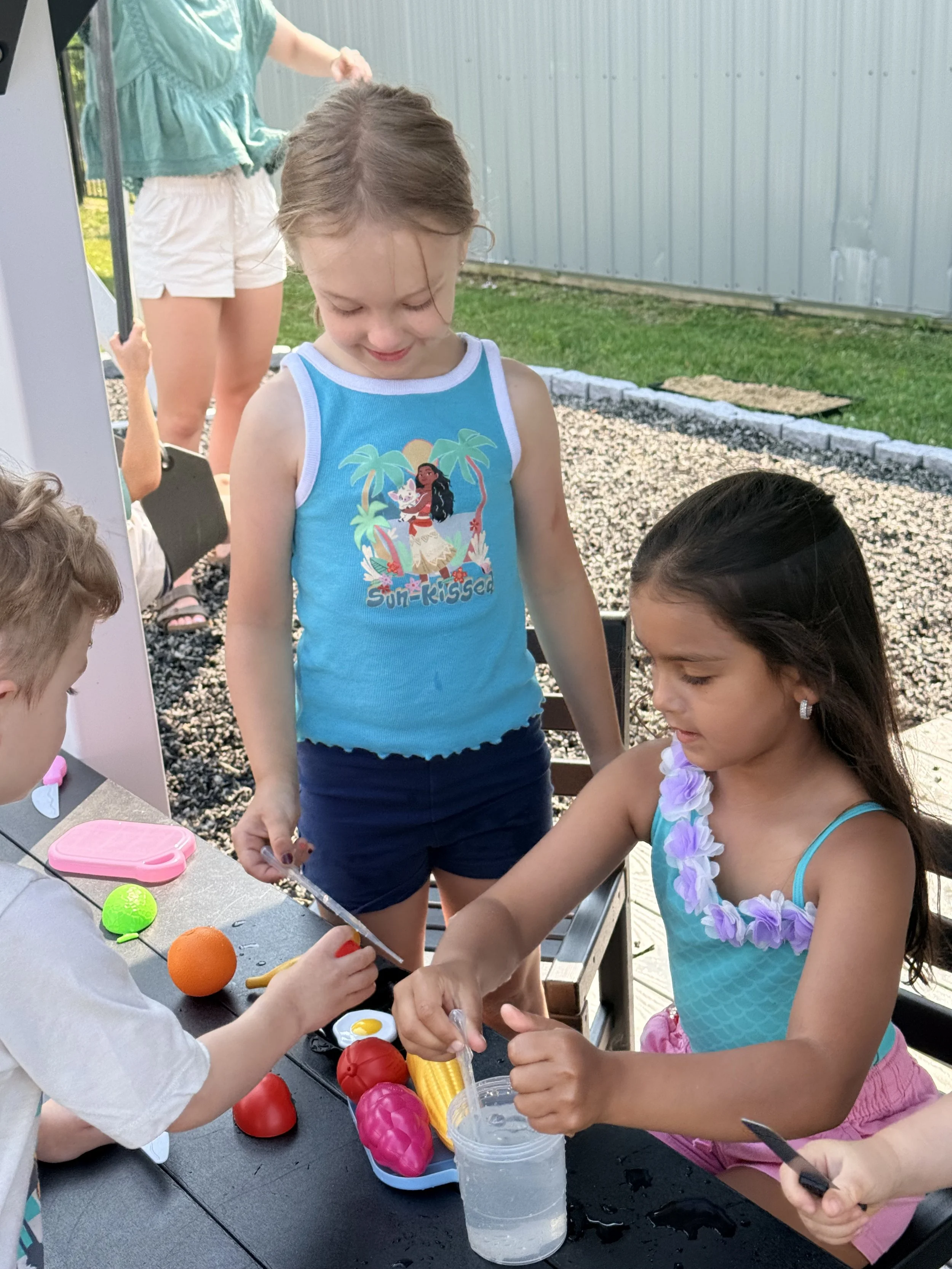 Preschooler gently hFriends playing restaurant together with pretend food outsideolding a snail she found outside