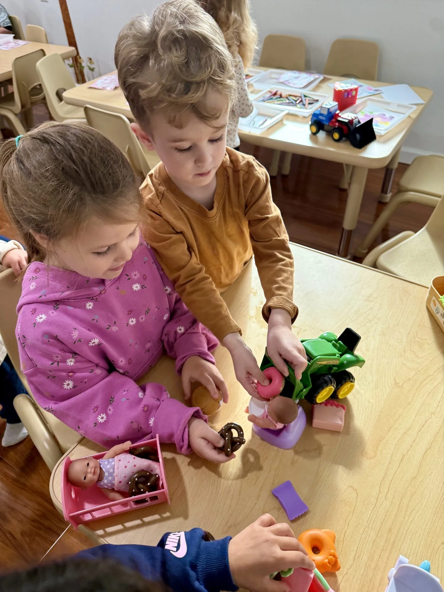 Two preschoolers playing side by side in the Discovery classroom