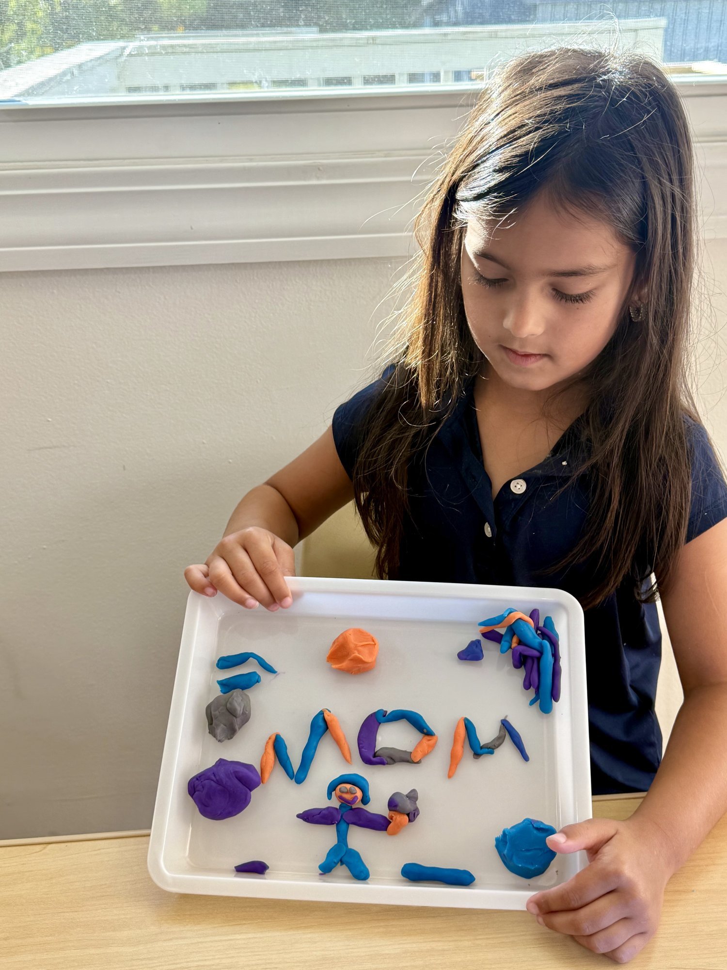 Preschooler spelling MOM with play dough letters