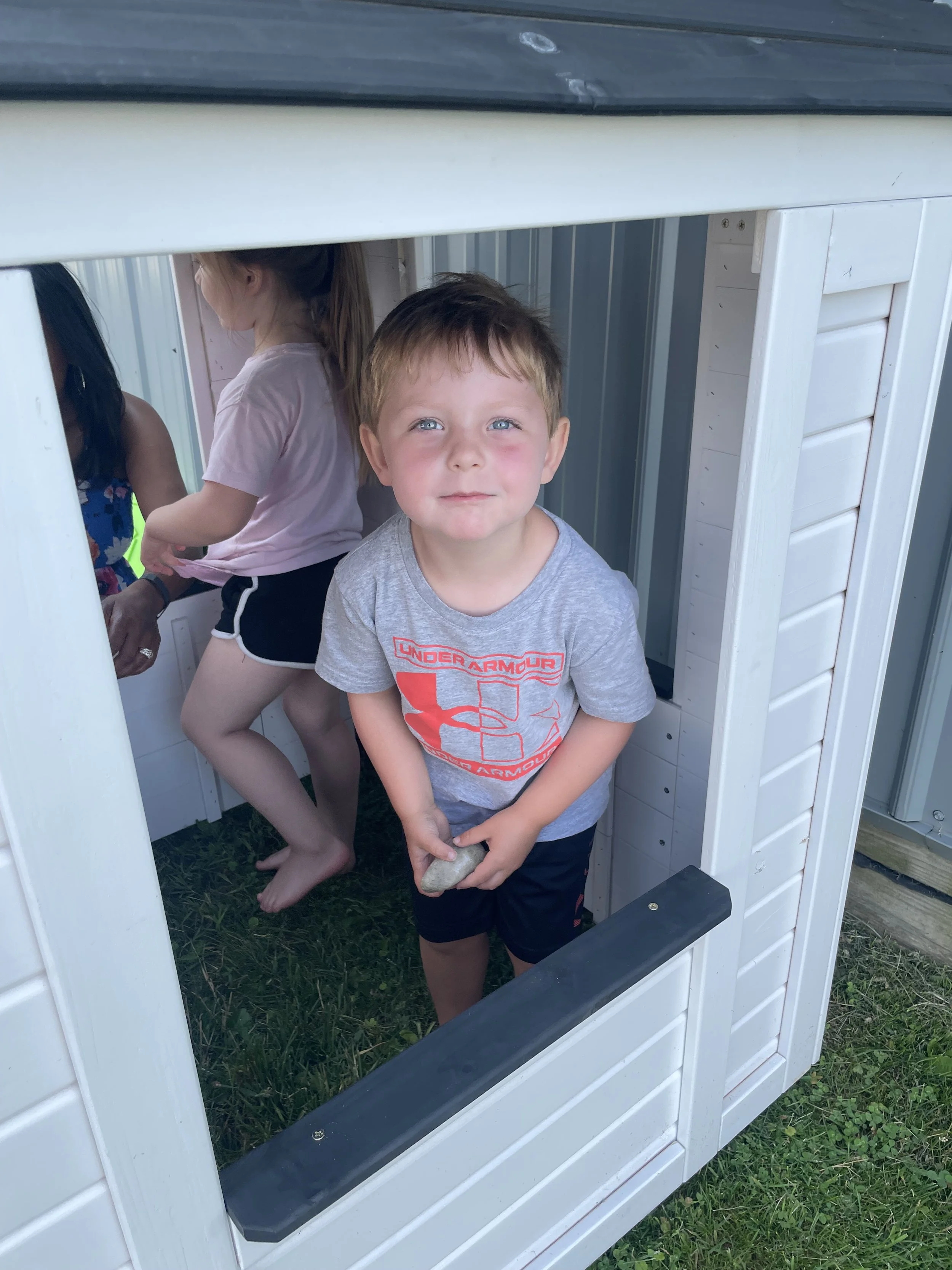 Smiling preschooler in the outdoor play house at Kids Come First