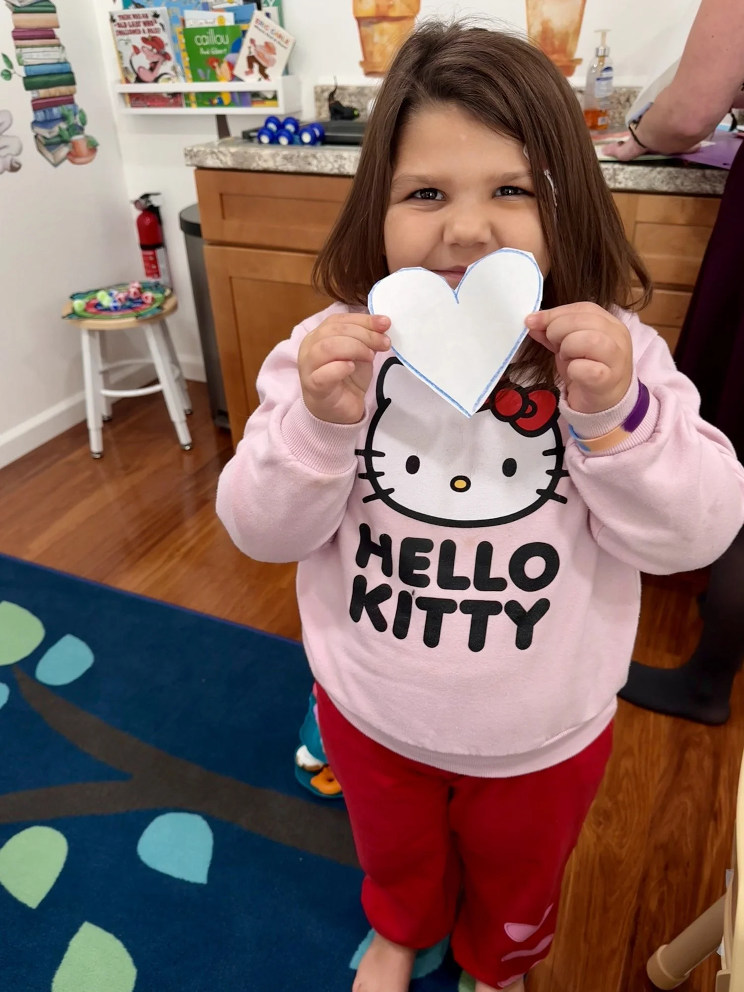 Smiling preschooler holding up a paper heart