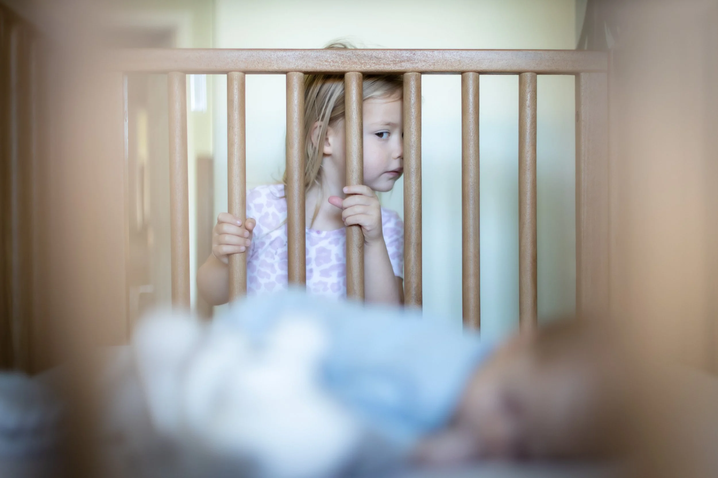 Big sister peeking at her newborn brother during an in-home newborn session in Thousand Oaks