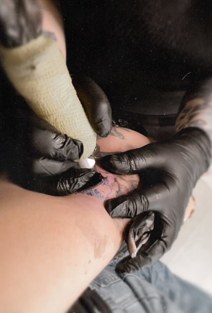 tatuoija tatuoi mustat hanskat kädessä tatuointia ihoon
