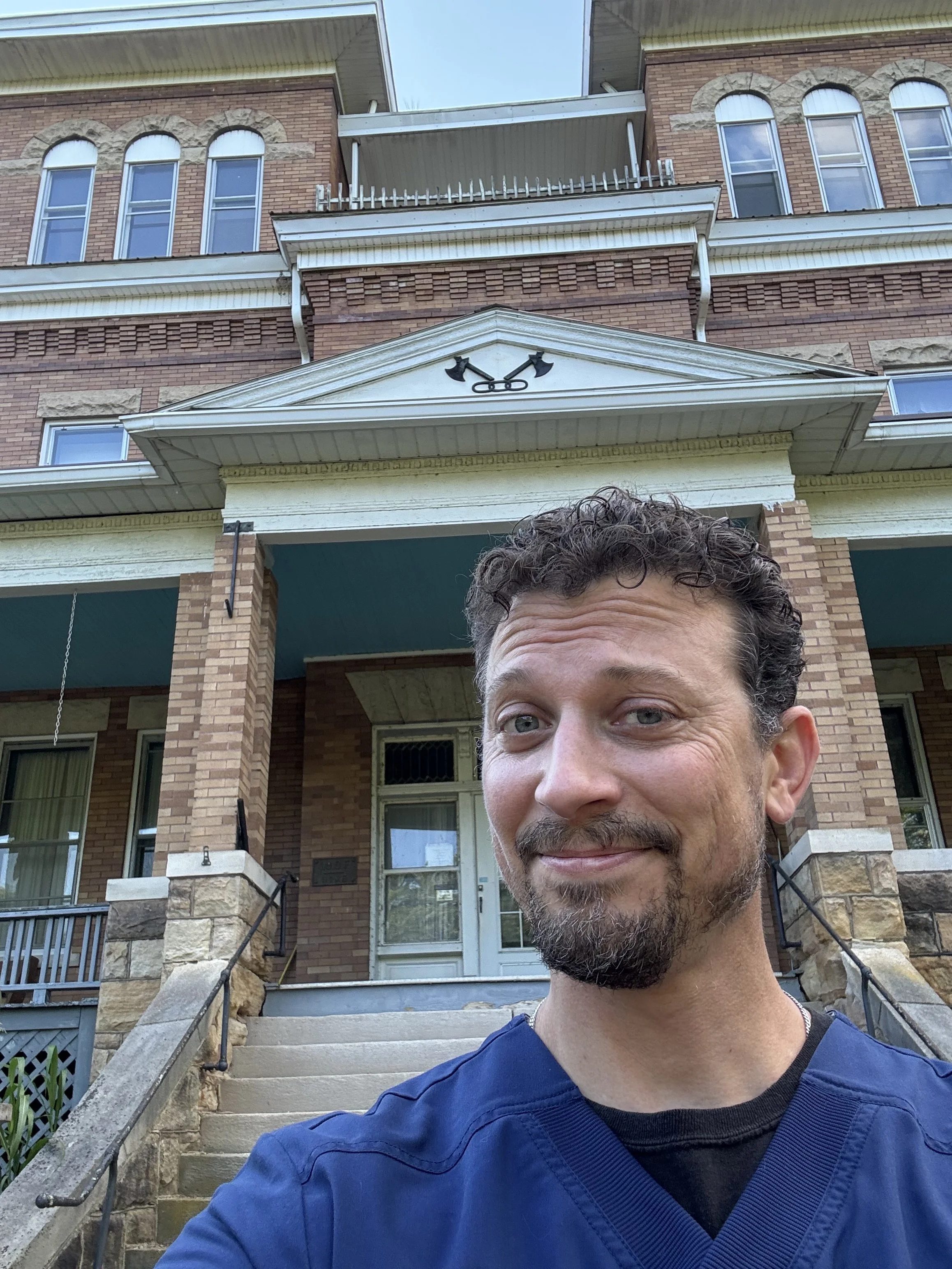 big smile in front of the front door of the oddfellow manor