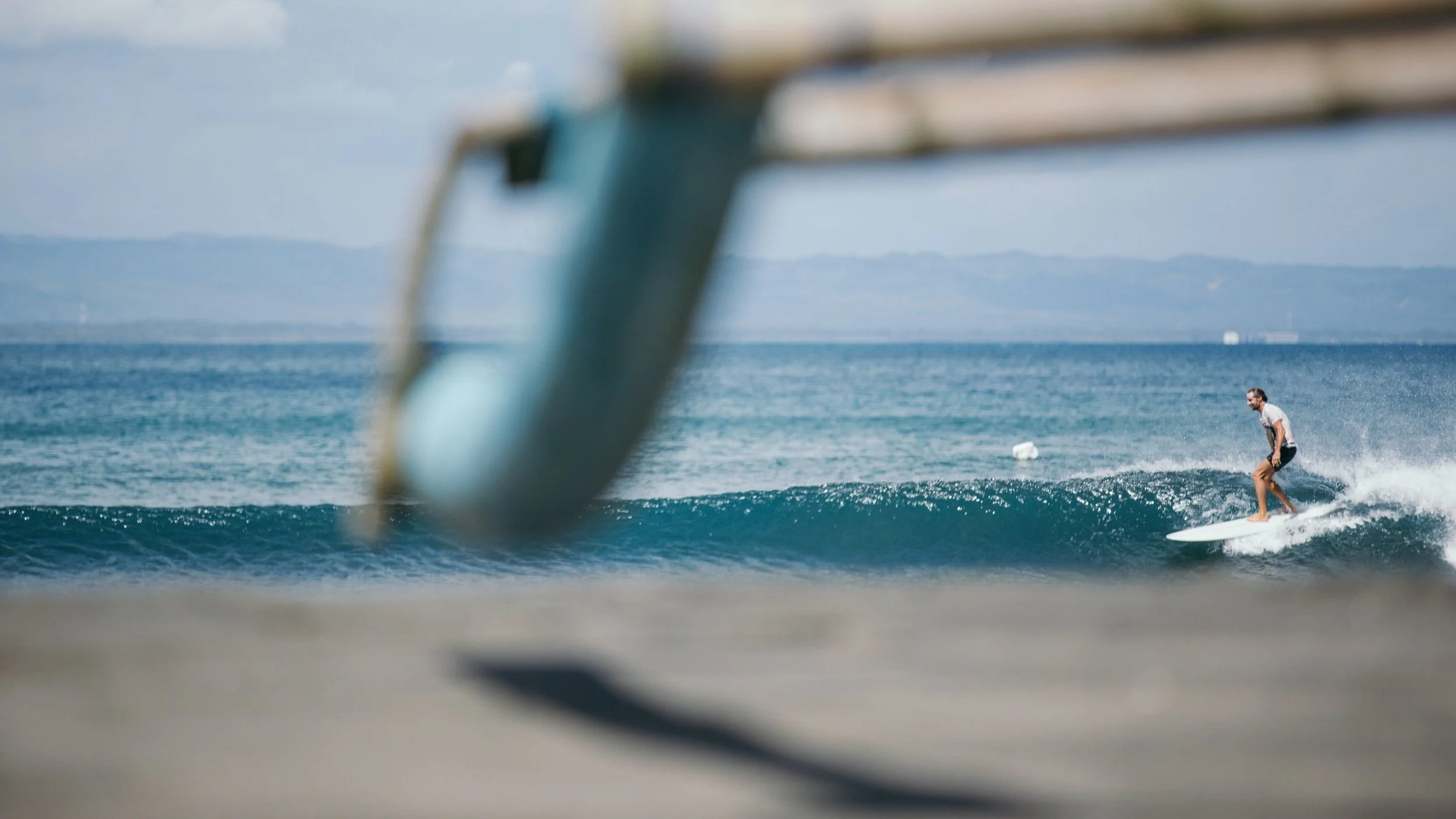 Person surfing on a wave in the ocean with blurred local boat foreground