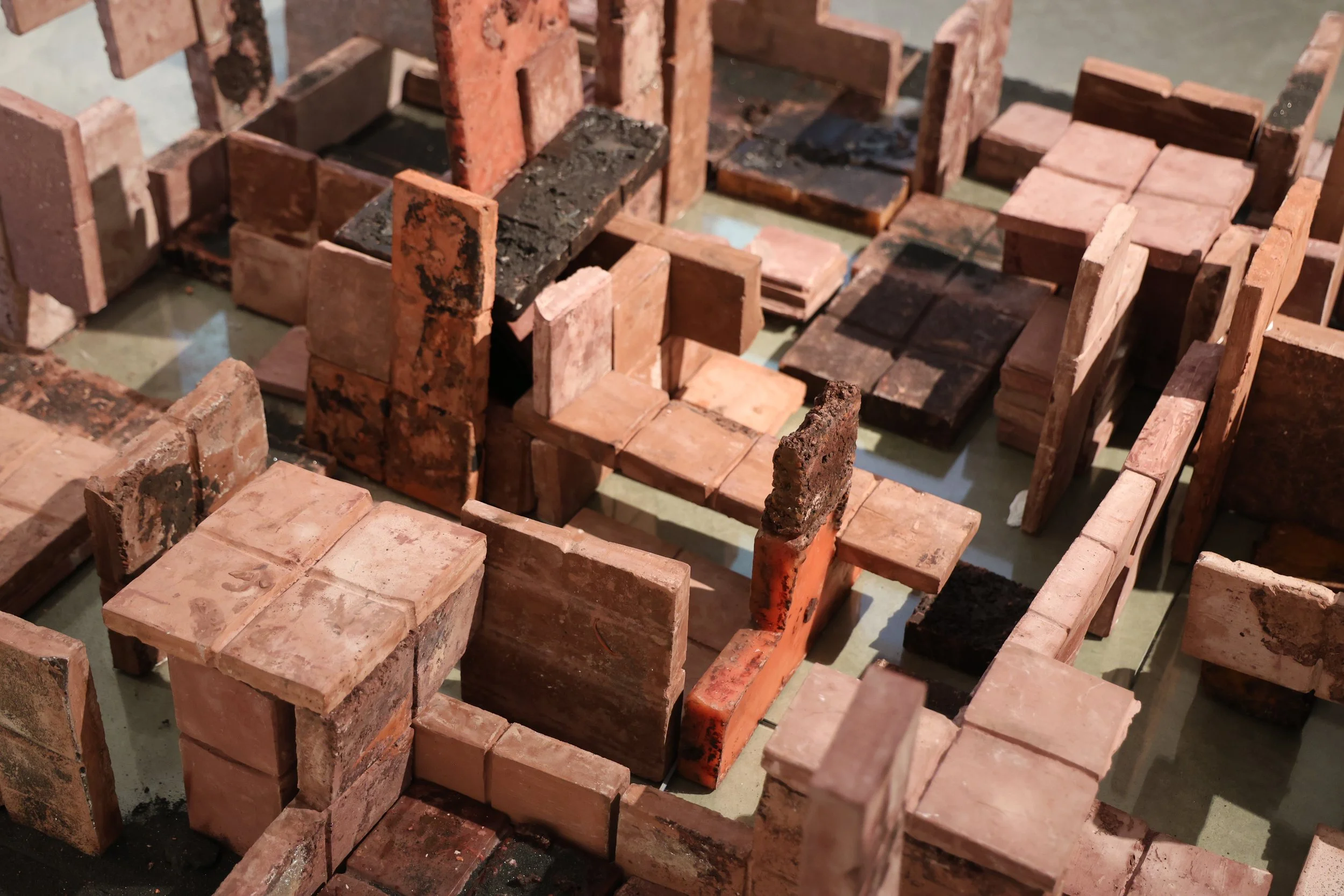 Zitz, Oil, Jolts, Soil, concrete, wax, glass, black sand, hair, and steel, 2025