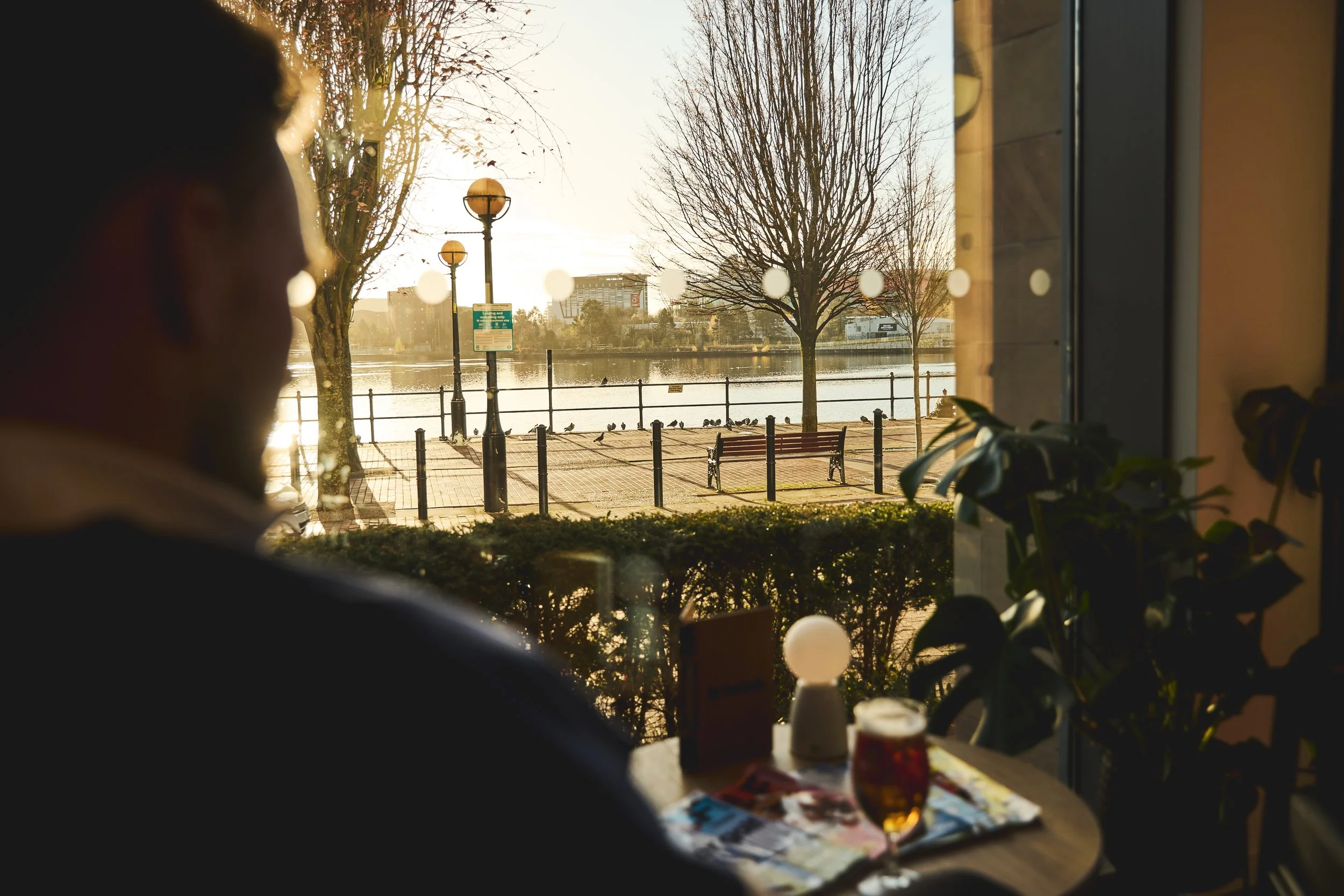 view of the water with man looking out of window with a beer