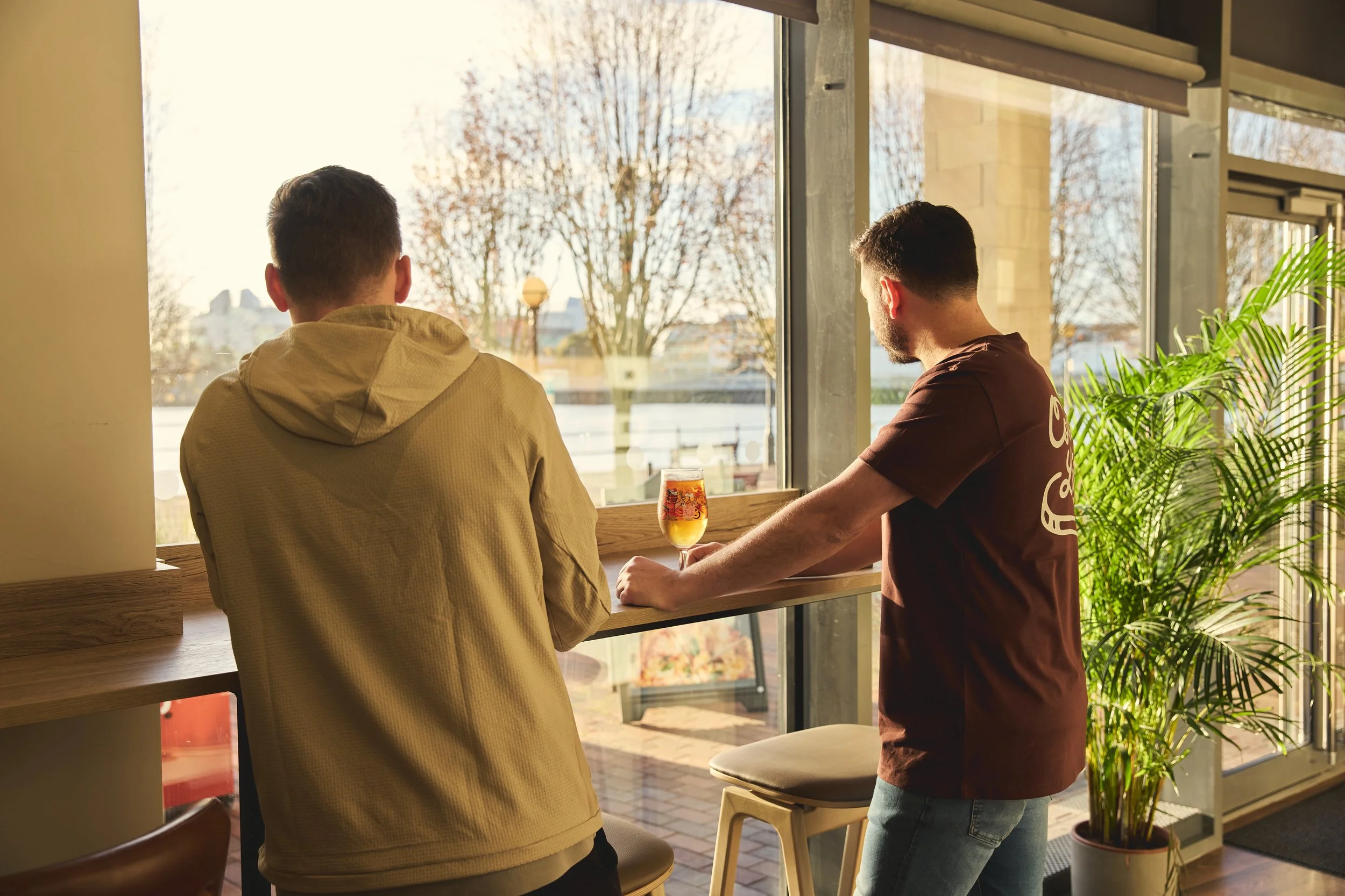 two men looking out at the view with beers