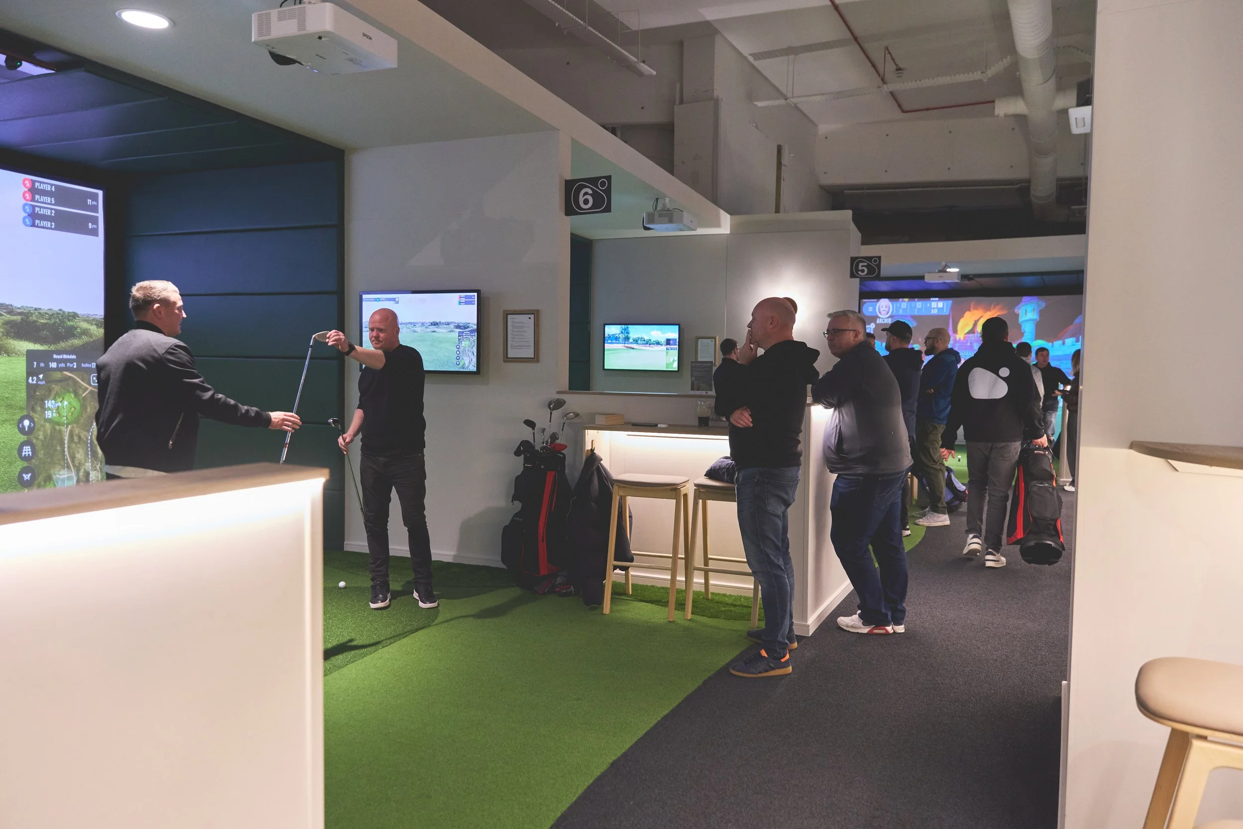 people playing golf in simulator bays at TeeClub