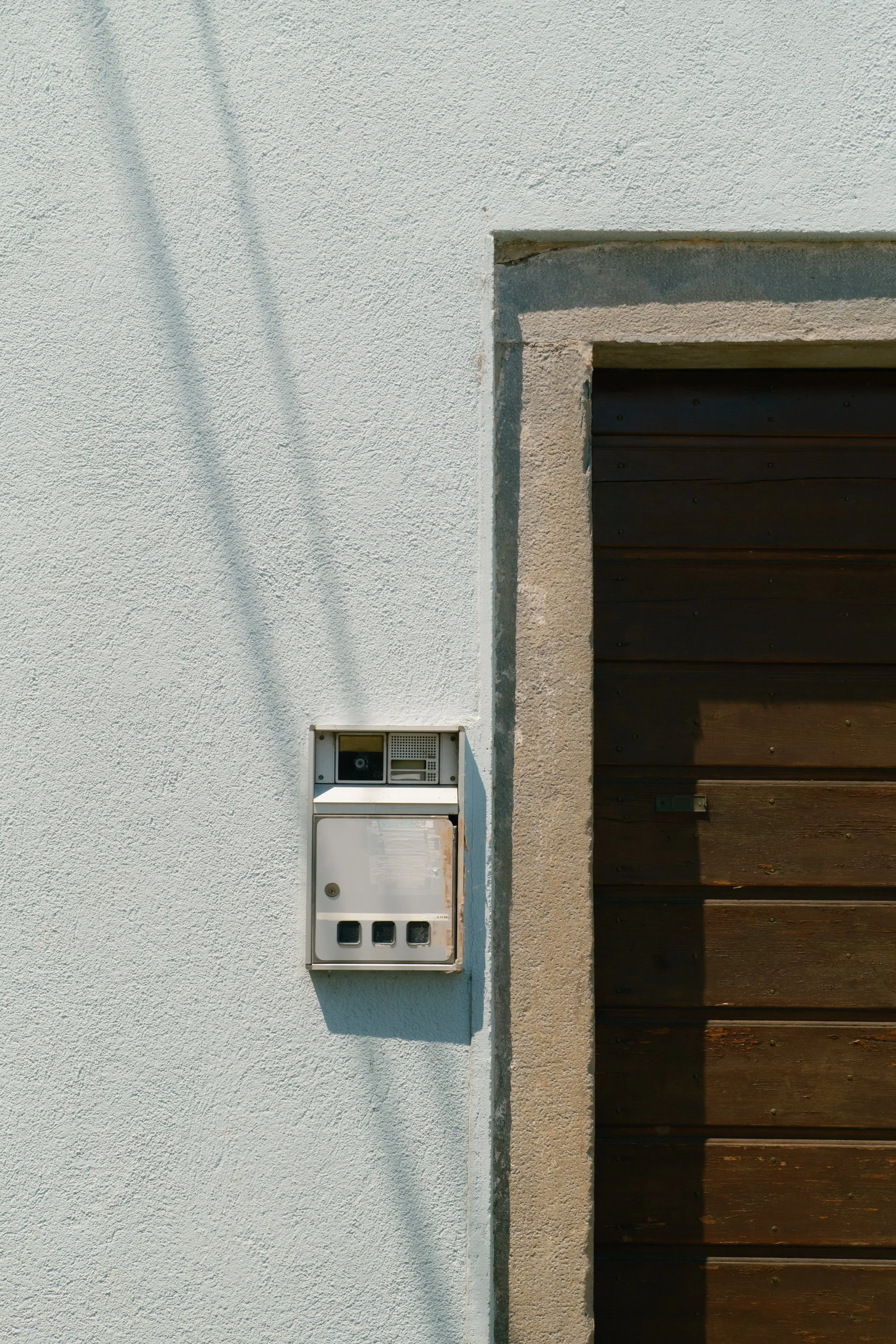 kaboompics_white-doorbell-on-light-blue-stucco-wall-with-wooden-door-42864.jpg