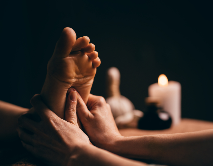 Foot massage therapy with dim lighting and candles in the background.