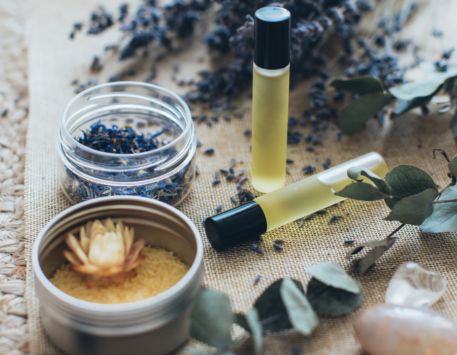 Aromatherapy setup with essential oils, dried flowers, and natural elements on a woven mat.