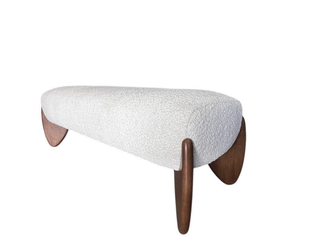 A modern, minimalist white upholstered bench with curved wooden legs.