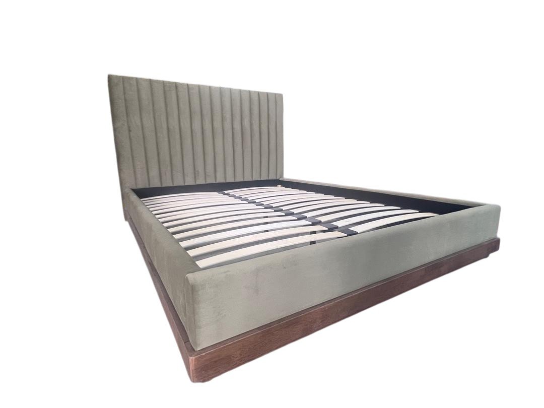A plush upholstered bed frame with a tall, vertically paneled headboard and a wooden base, without a mattress.