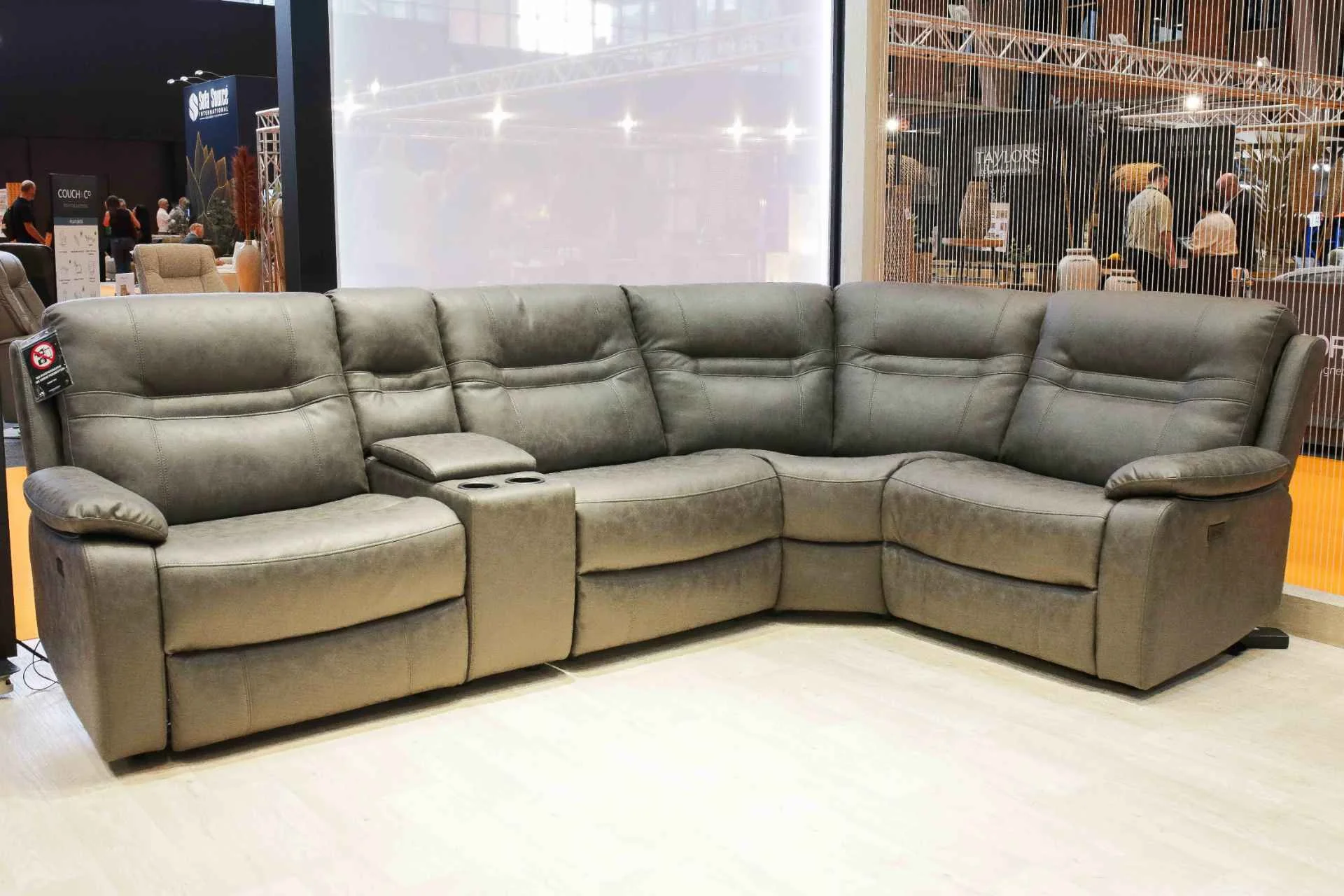 Gray sectional sofa with built-in cup holders and a recliner in furniture store or showroom.