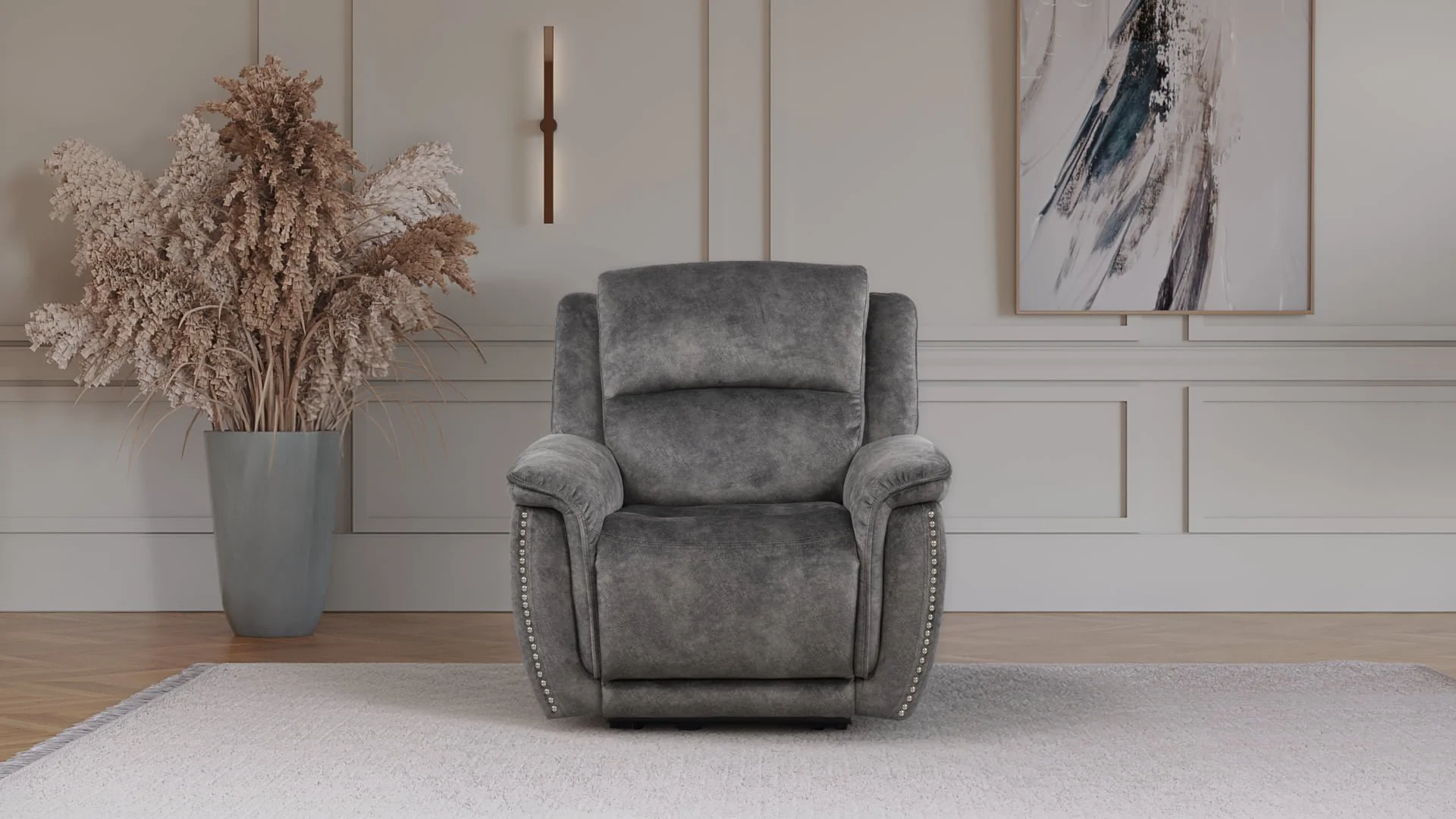 Gray upholstered armchair centered in a room with white paneled walls, next to a tall gray vase with dried pink and beige pampas grass, and a large abstract painting on the wall.