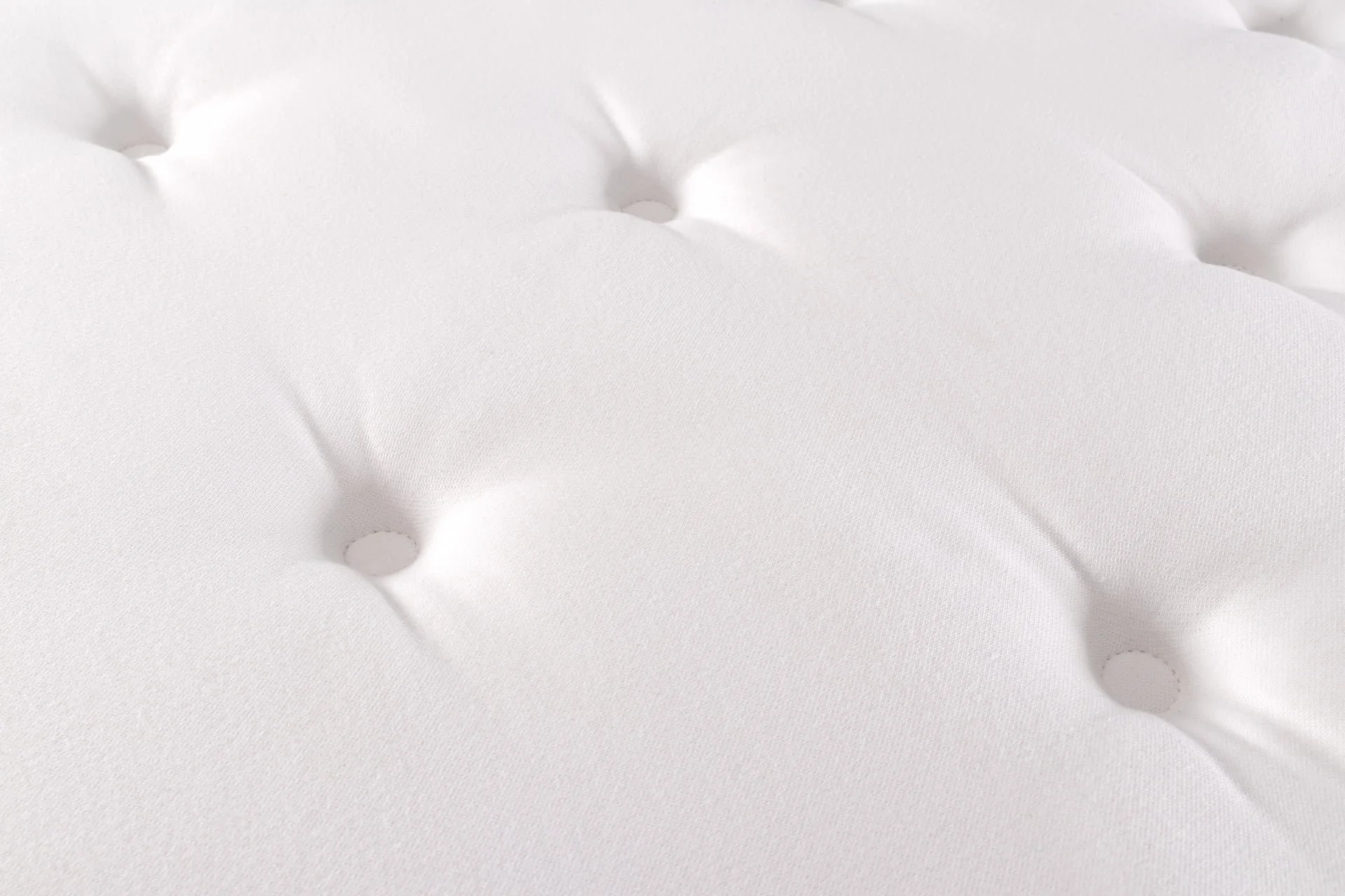 Close-up of a white mattress with tufted buttons.