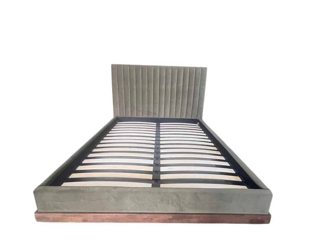 A bed frame with a padded headboard and metal slats, empty of a mattress.