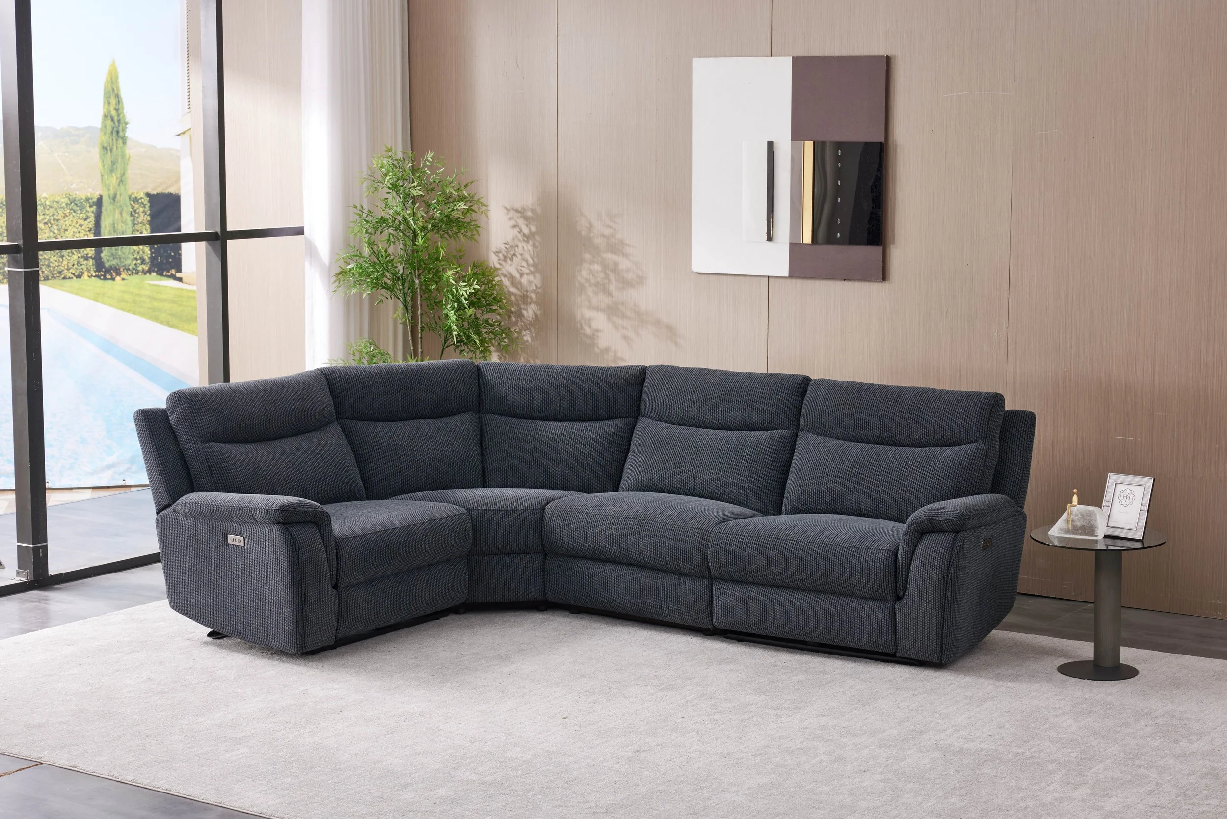Modern living room with a large dark gray sectional sofa, a window with cityscape view, and abstract black and white art on a black accent wall.