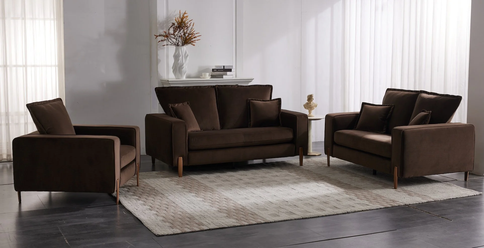 Living room with brown sofa, two matching armchairs, a beige rug, and decorative items including a white vase with dried flowers, a statue, and books.