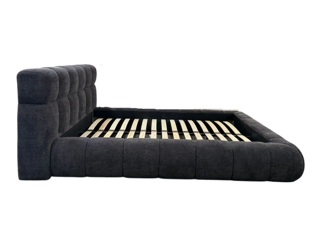 Dark gray upholstered bed frame with a tufted headboard, no mattress, and visible wood slats for supporting a mattress.