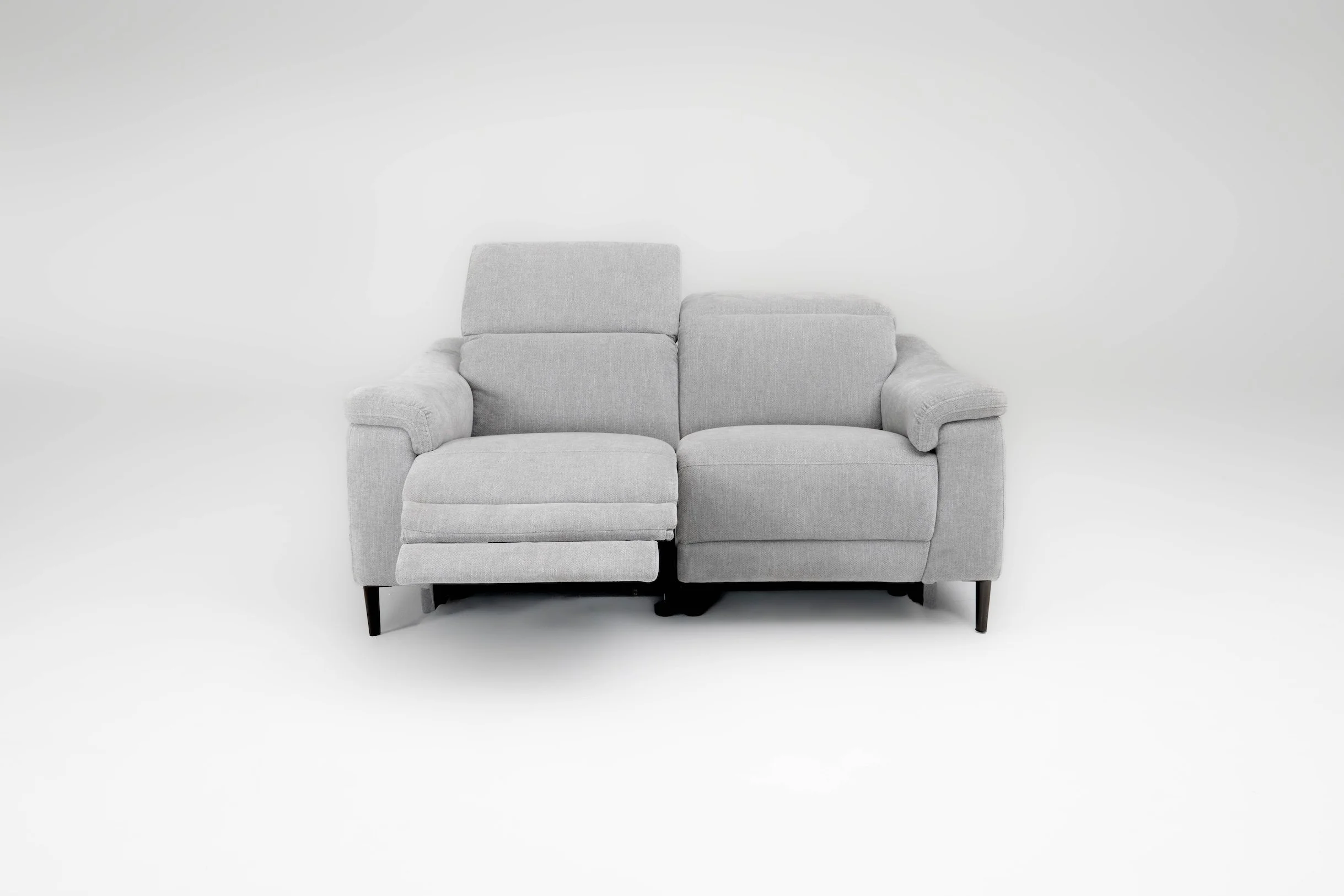 A light gray, two-seat sofa with one side extended into a chaise lounge, set against a plain white background.