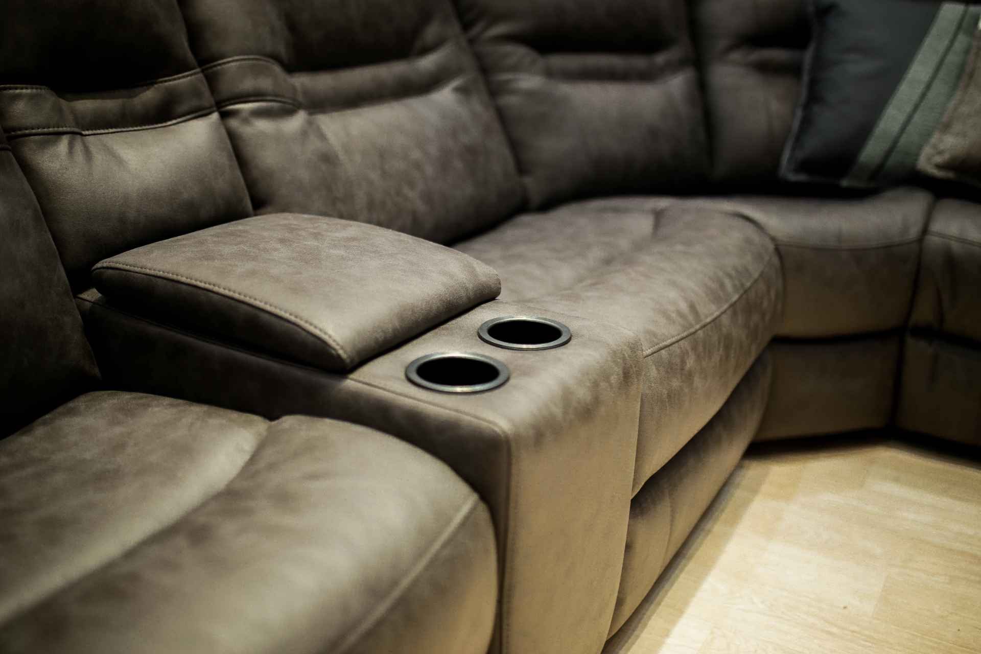 A brown sectional sofa with cup holders built into the armrest.