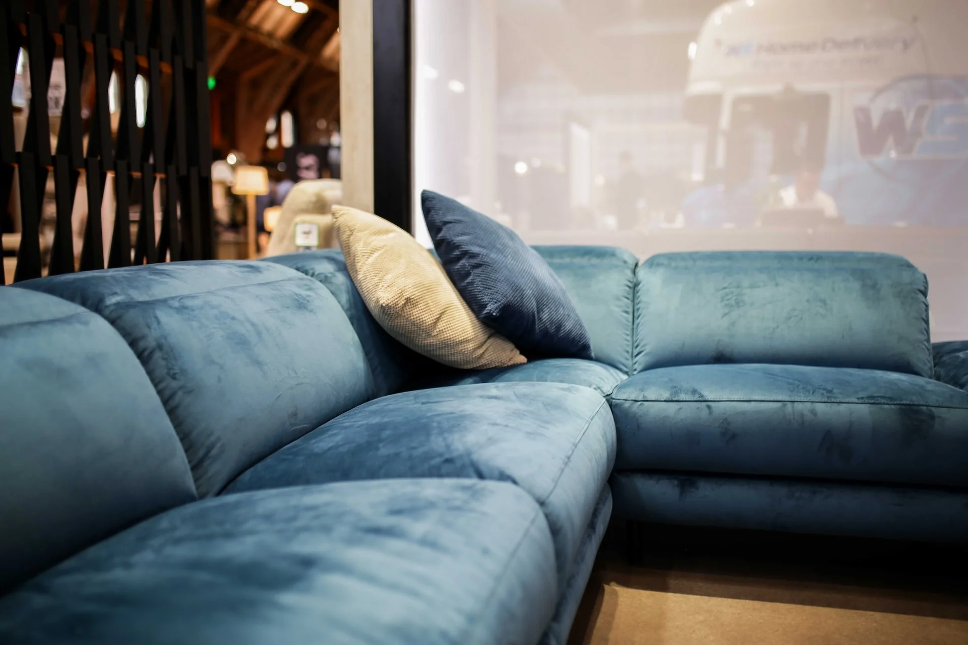 Blue velvet sectional sofa with beige and navy throw pillows in a cozy furniture store