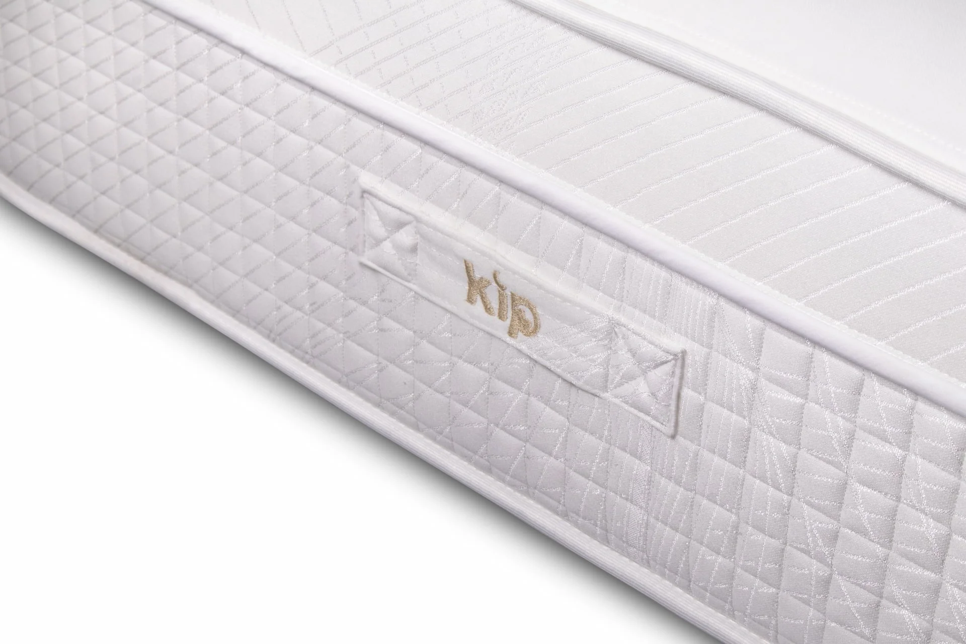 Close-up of a white mattress with a quilted pattern and a small embroidered tag that says 'kûp'.
