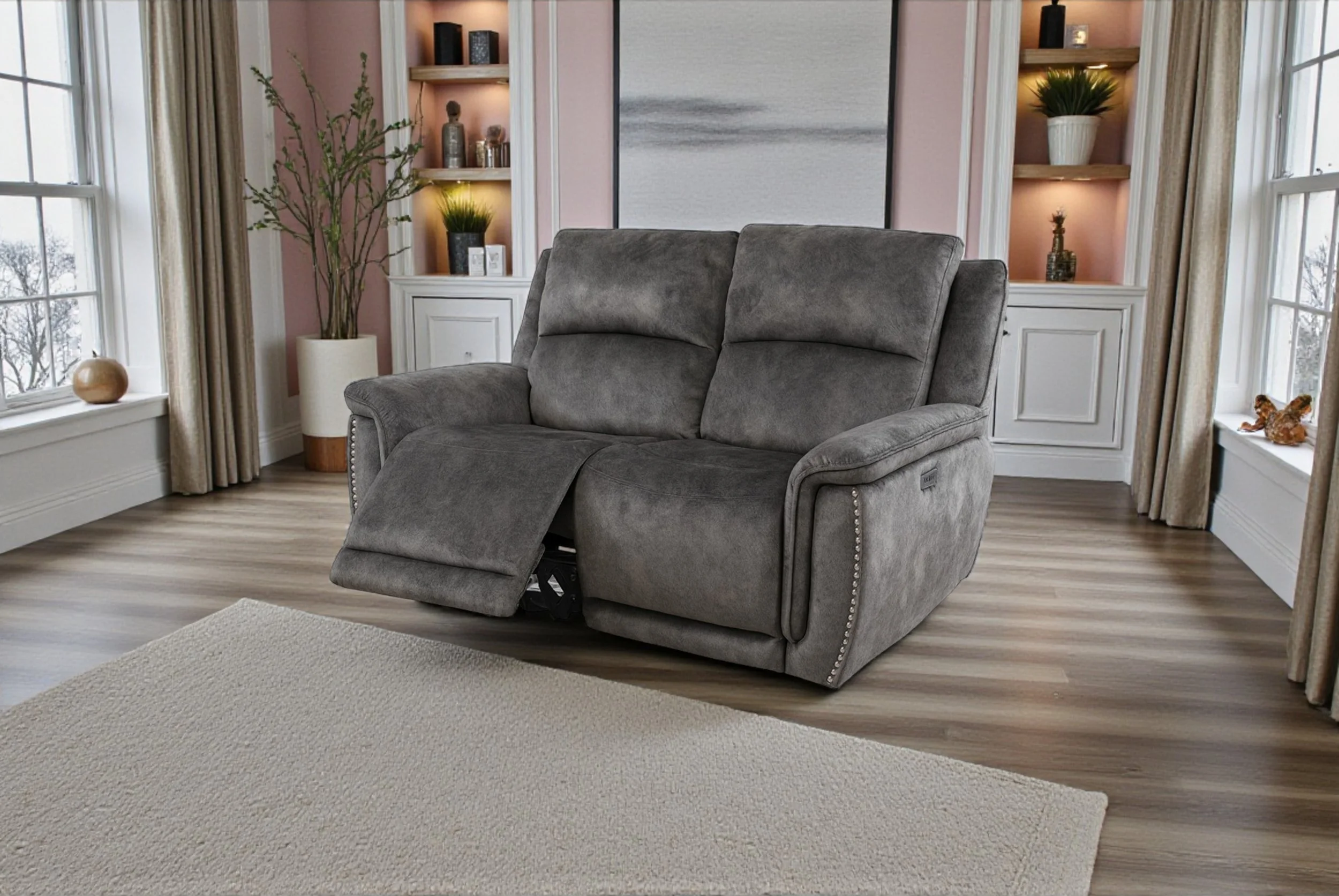 Living room with a gray sofa and a green potted plant next to large window showing trees outside.
