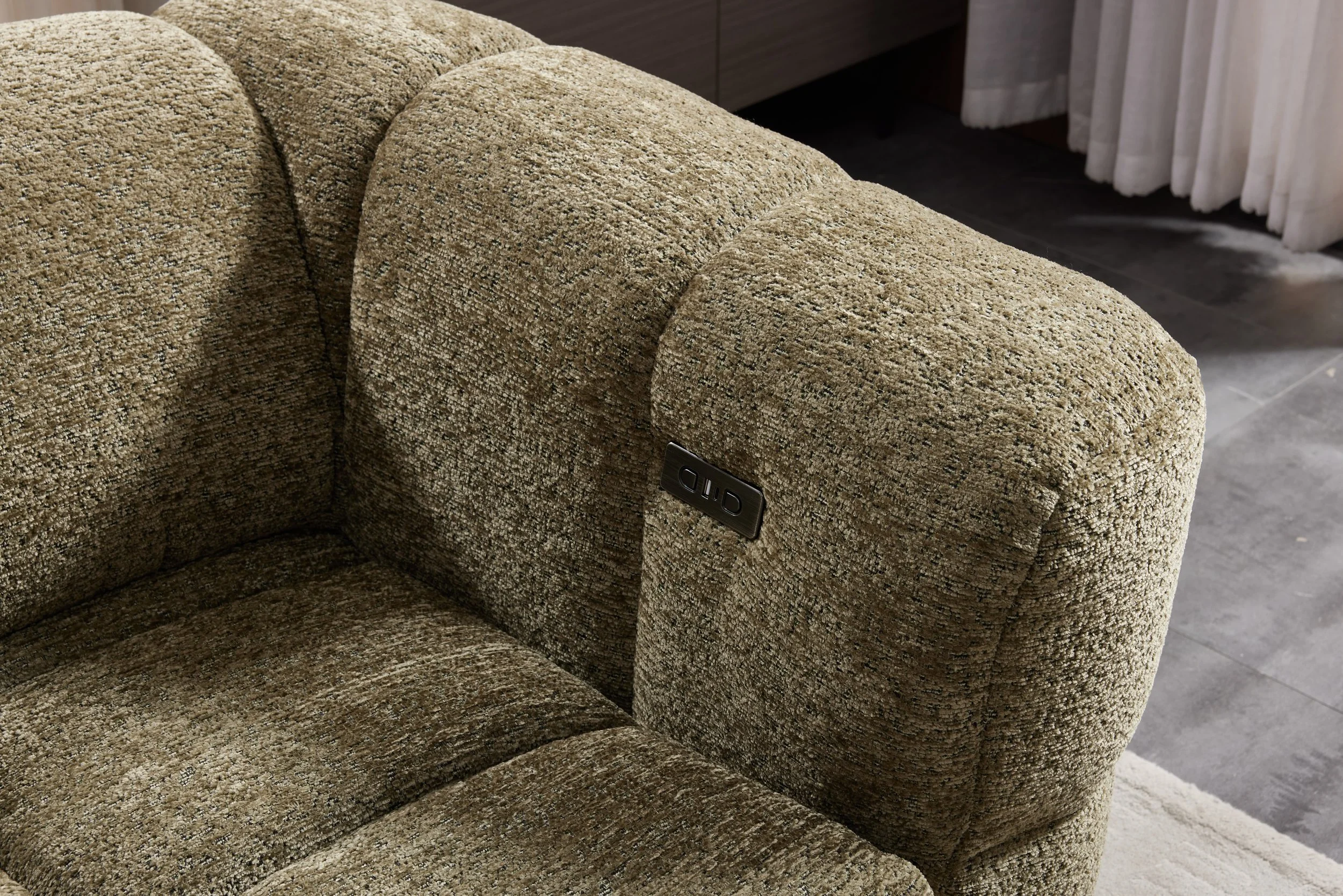 Close-up of a brown textured fabric armrest of a sofa with a control panel labeled 'OHD' on the side.