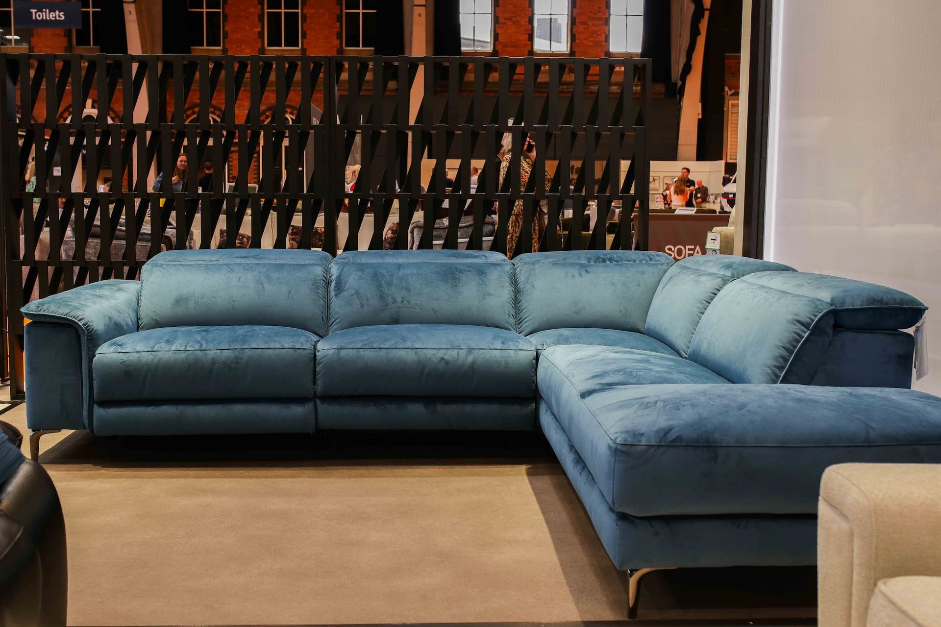 A large L-shaped blue velvet sofa displayed in a furniture store.