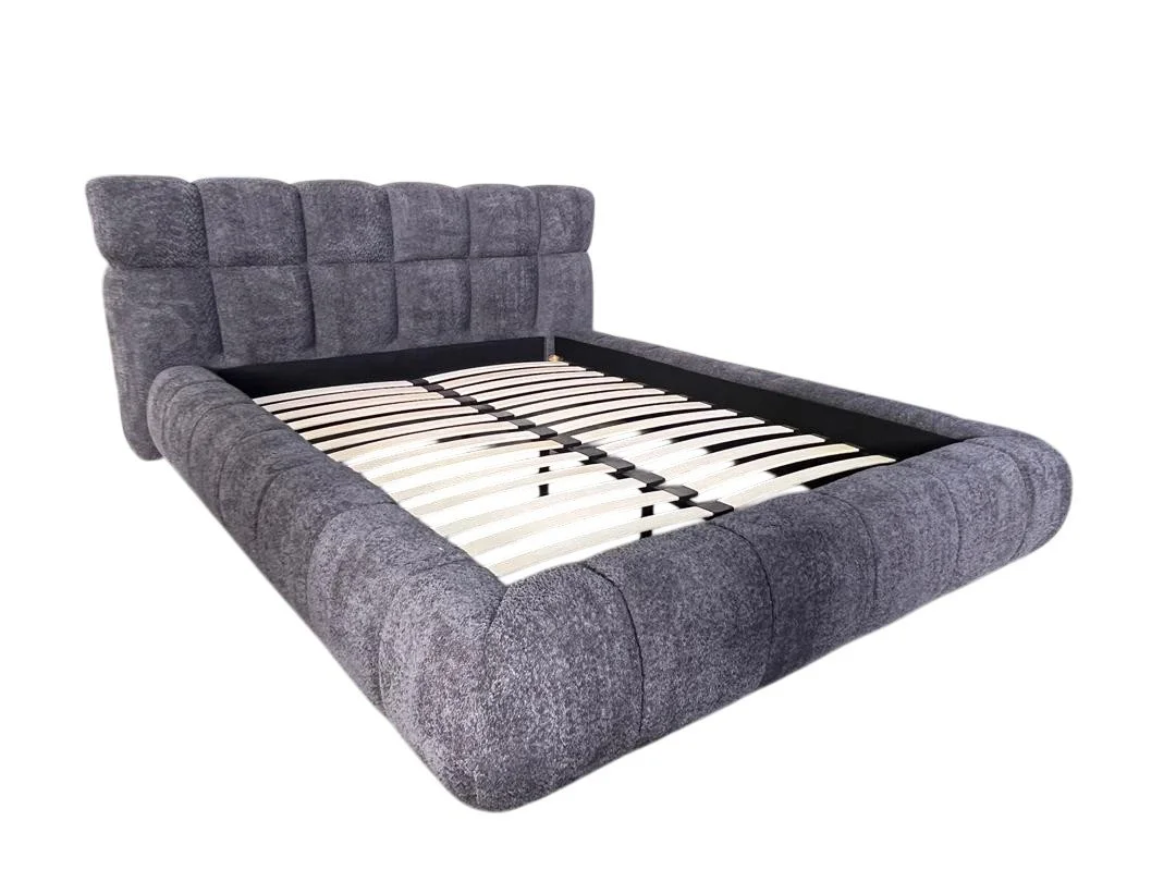 A gray upholstered bed frame with a padded headboard and wooden slats for a mattress.