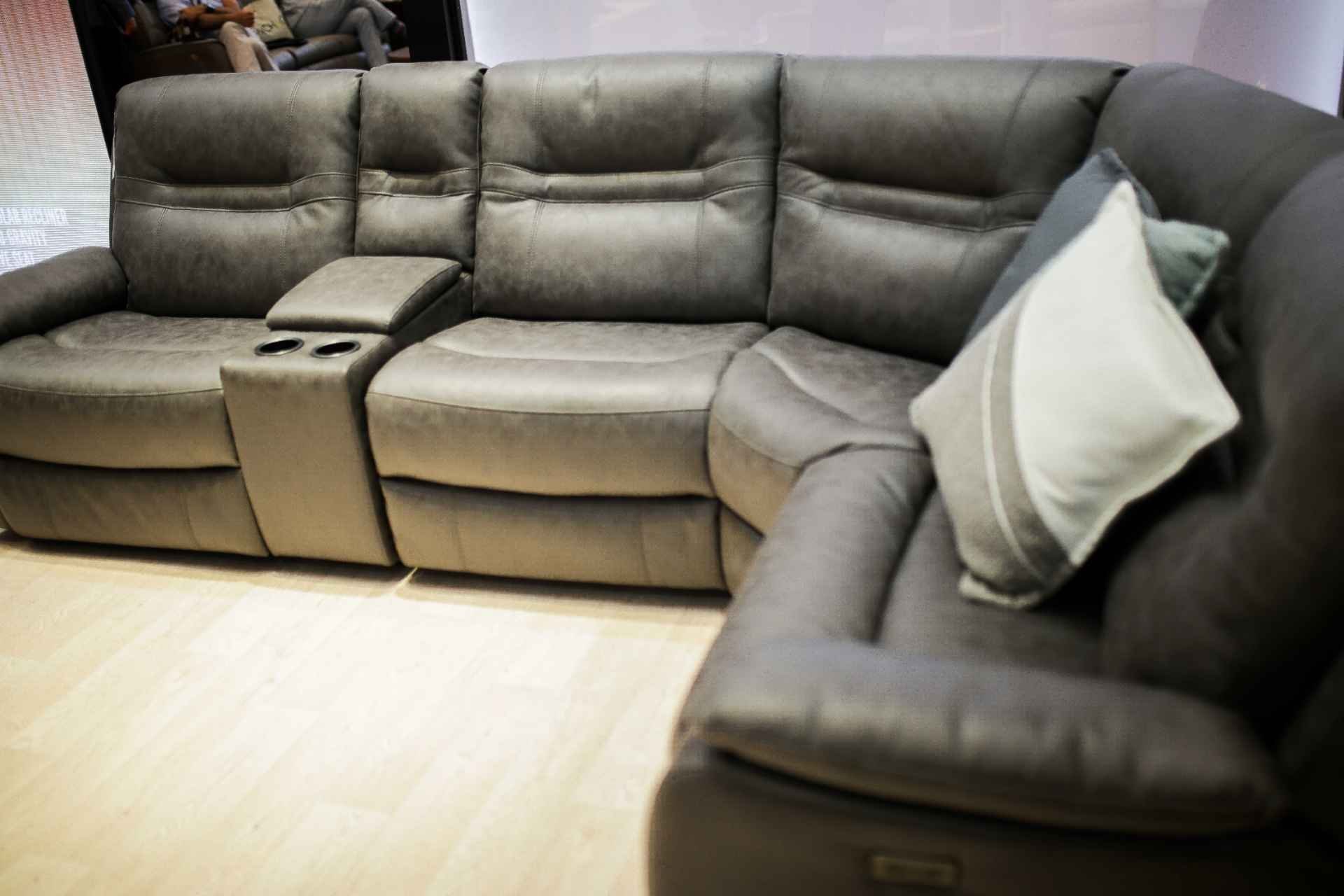 A gray sectional sofa with a pillow on the right side in a room with a light-colored floor.