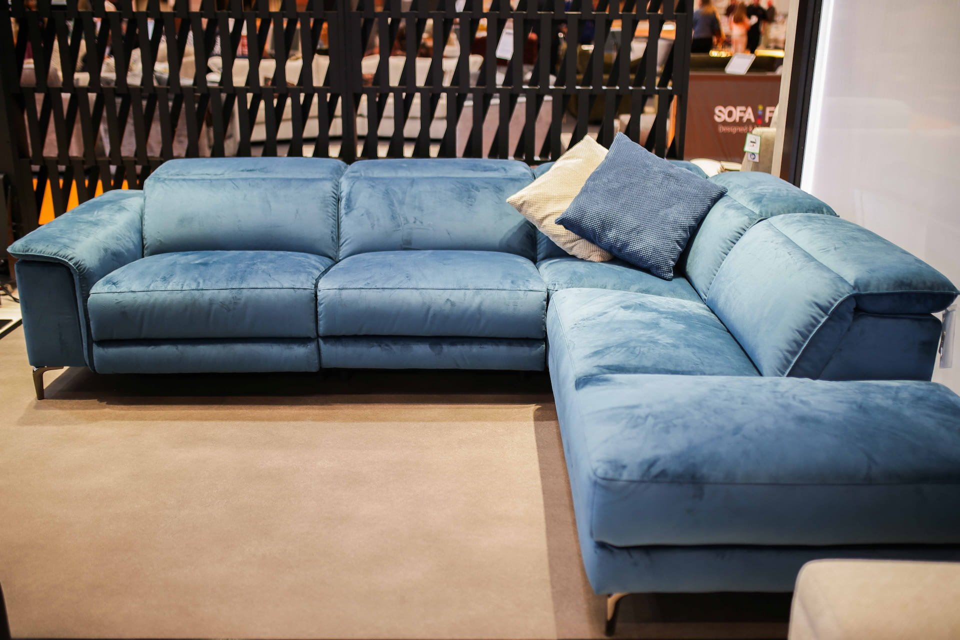 Blue sectional sofa with two pillows on a beige carpet in furniture store.