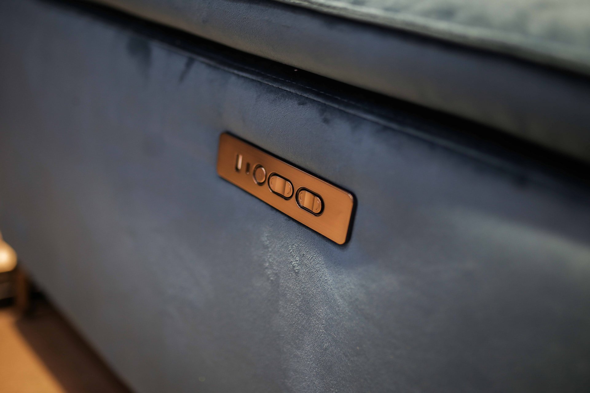 Close-up of a control panel on a blue appliance with two toggle switches, gold-colored in appearance.