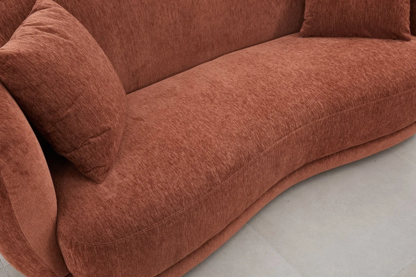 A close-up of a red upholstered sofa with matching cushions on a tiled floor.