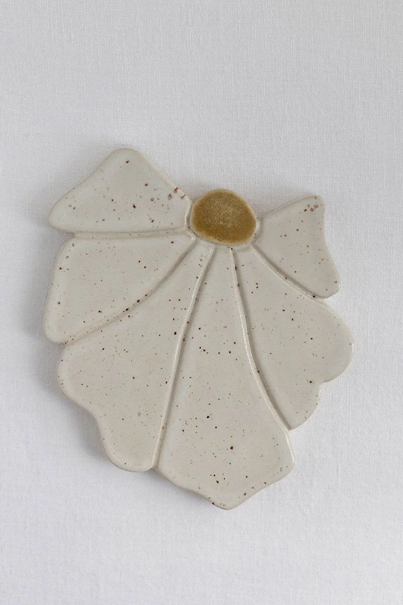 Kuvassa on valkoinen keramiikkalautanen, joka on muotoiltu jouluruusu-lehdeksi.