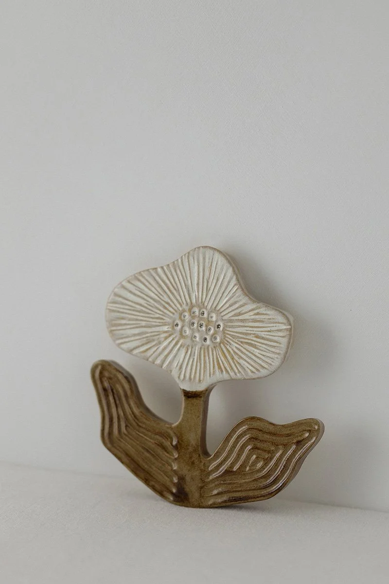 Kuvassa on keramiikkapunainen kukka ja lehti sekä valkoinen kukka, jotka ovat näyttävän muotoisia ja käsinmaalattuja.