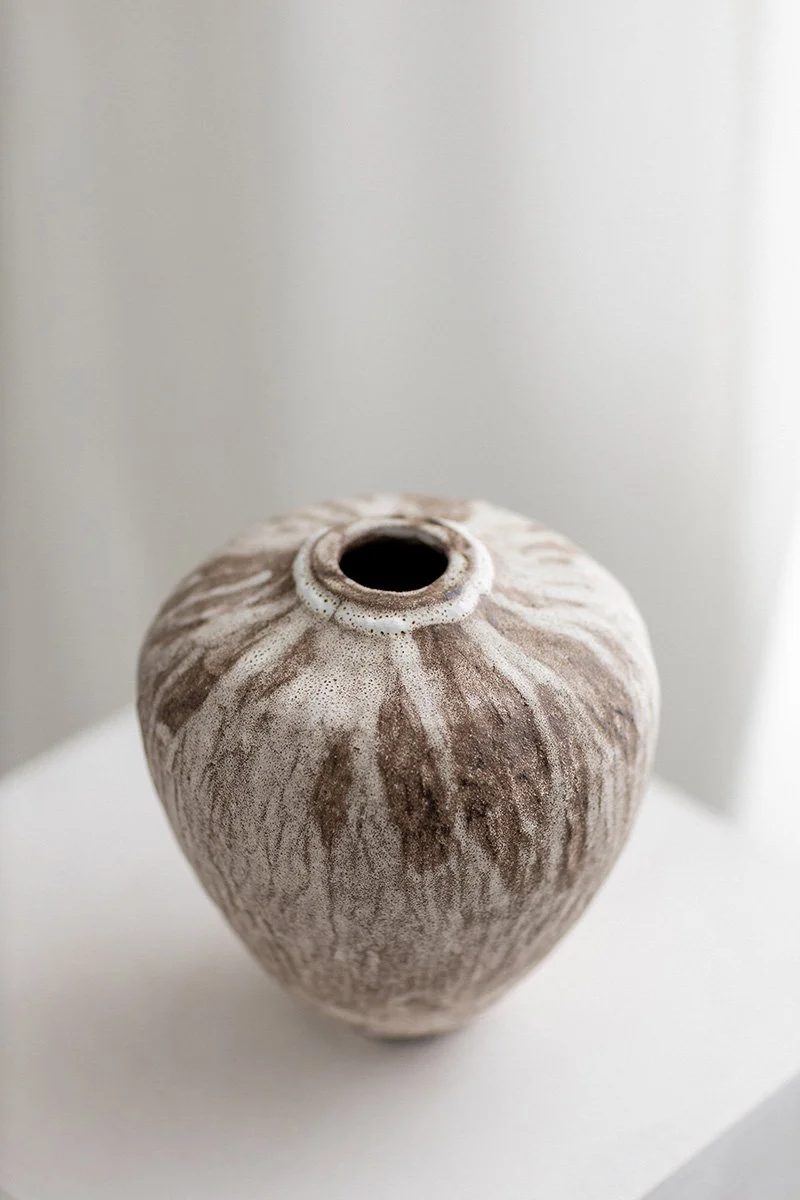 Mustasta kivitavarasavesta valmistettu vaasi, jossa valkoinen lasitus pinnalla. 