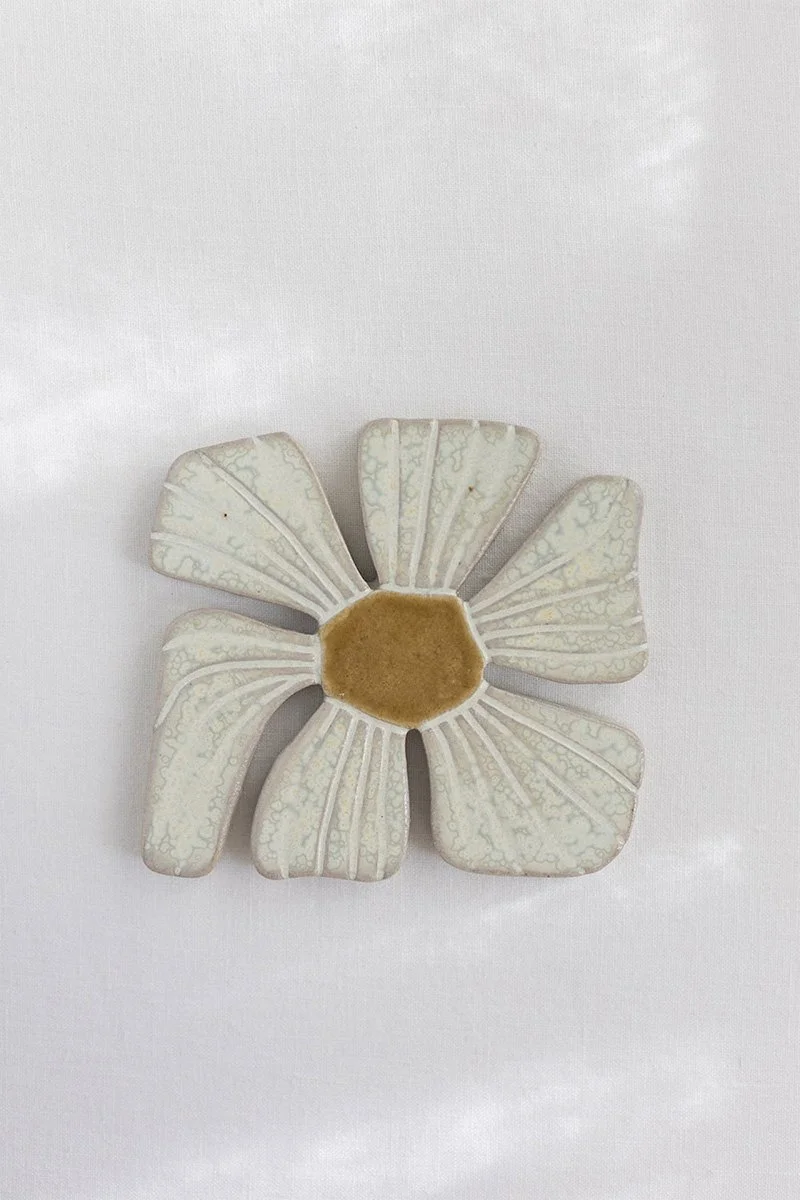 Kukkamuotoinen tarjotin, jossa on keskellä hunajaa.