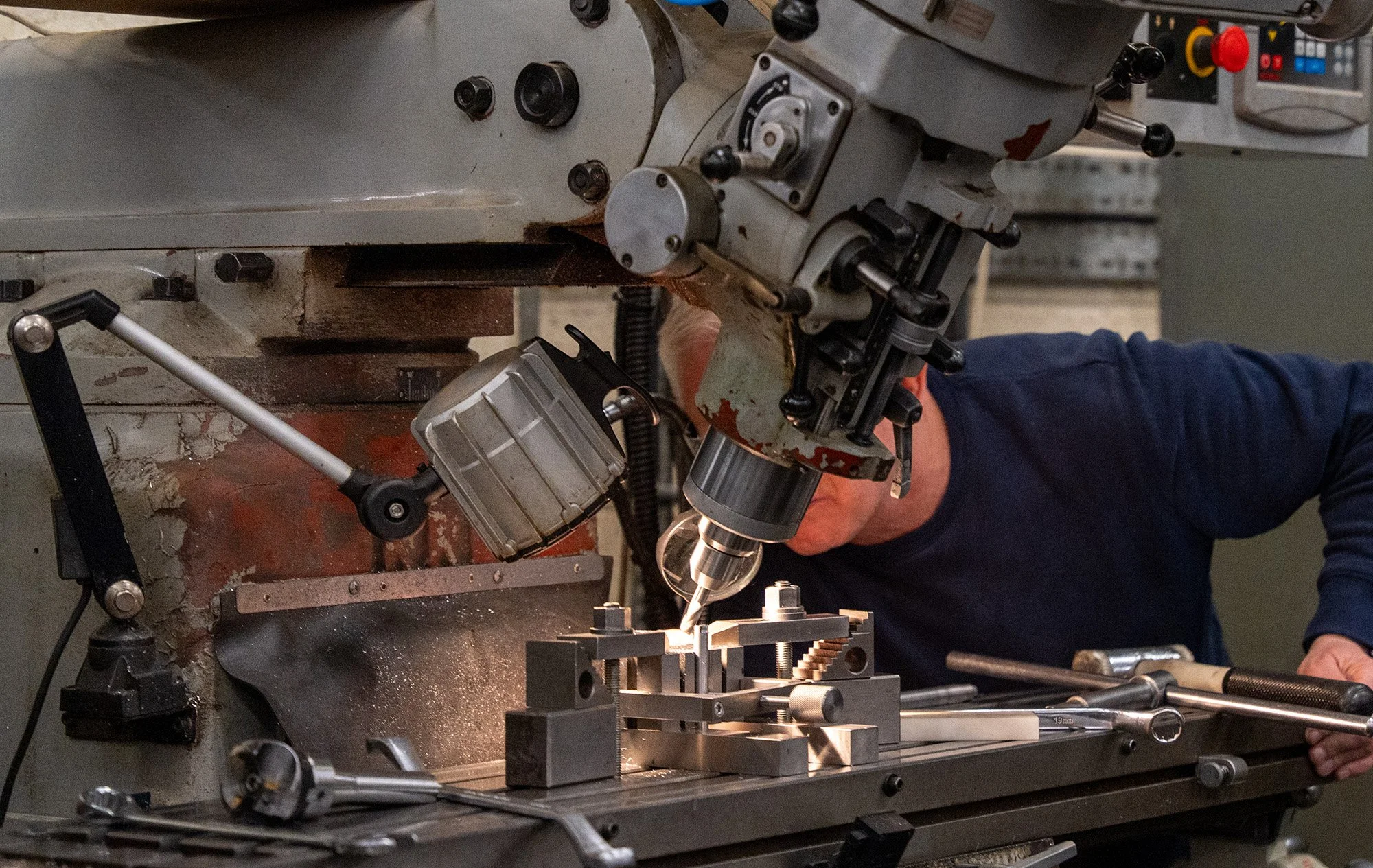 Person operating a vertical milling machine, machining a metal component.