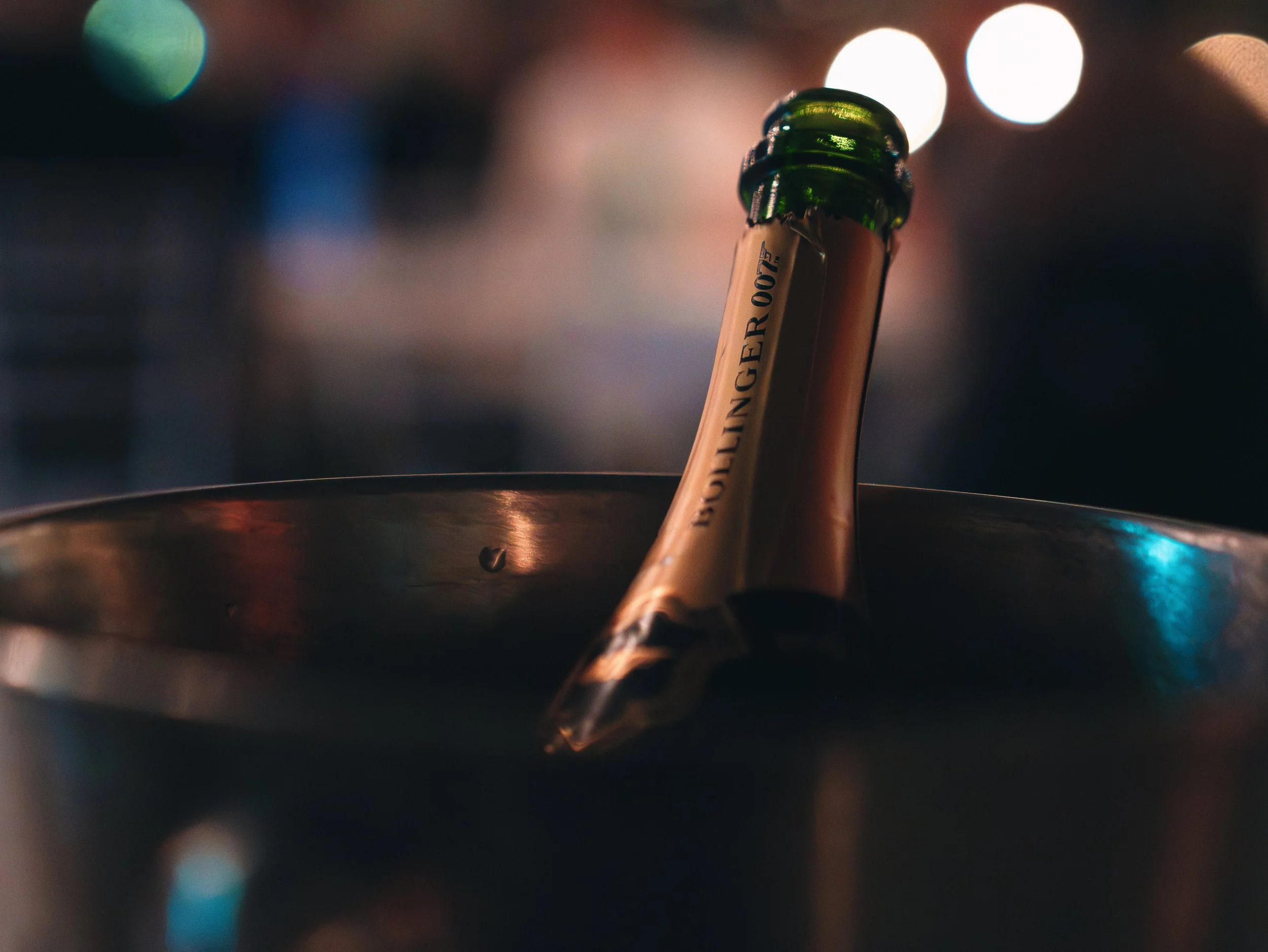 A champagne bottle in an ice bucket with blurred bokeh lights in the background.